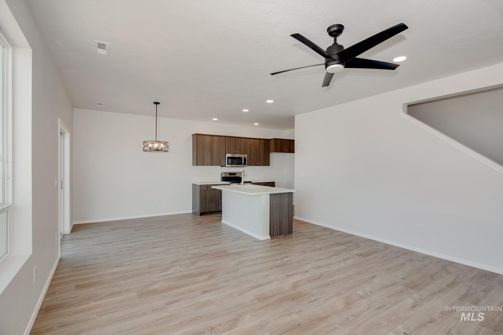 Kitchen with an island with sink, open floor plan, recessed lighting, light wood finished floors, and a chandelier