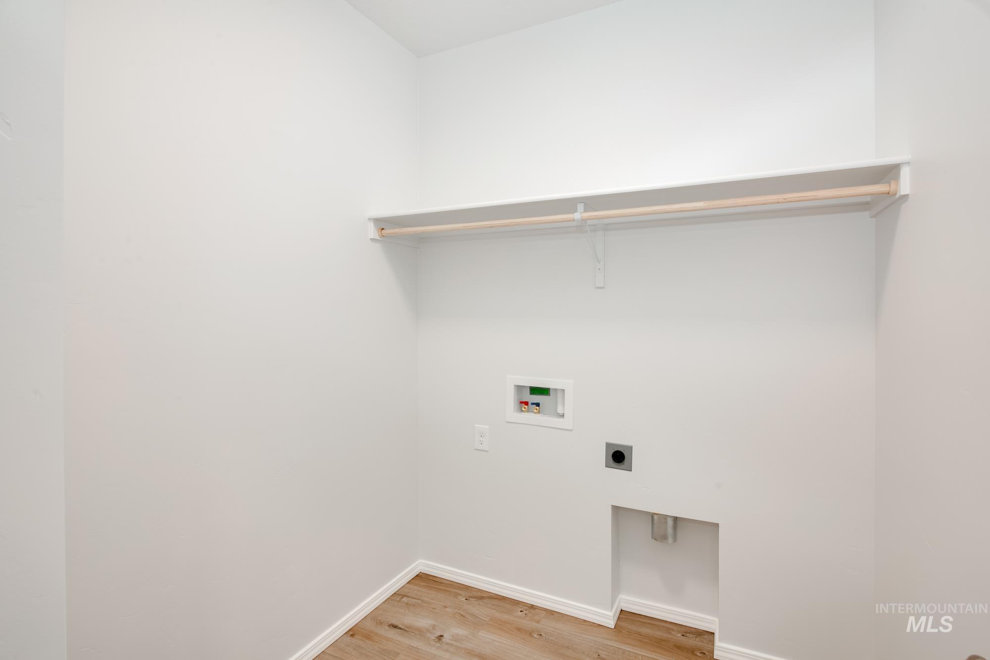 Washroom with light wood-type flooring, hookup for an electric dryer, and washer hookup