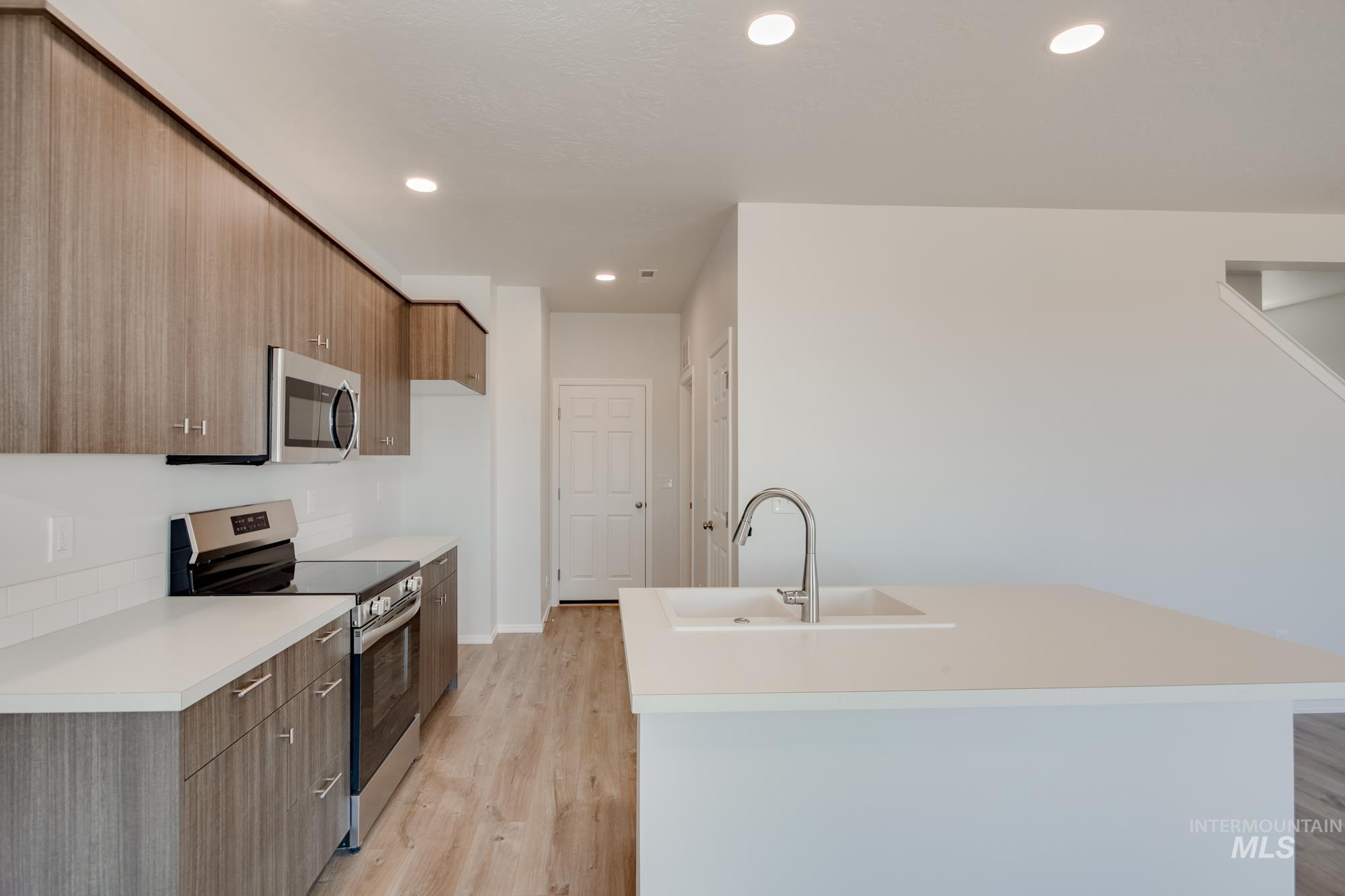 Kitchen featuring stainless steel appliances, modern cabinets, recessed lighting, light countertops, and light wood-type flooring