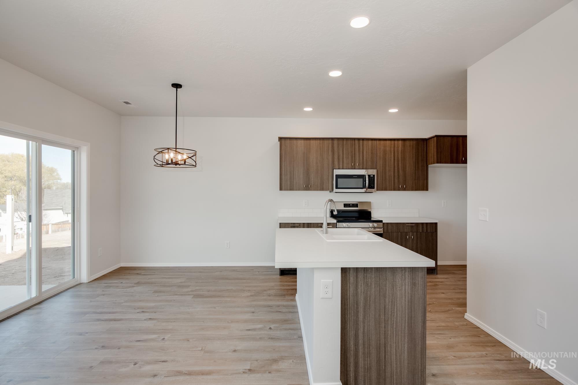 Kitchen with a center island with sink, light countertops, light wood-style floors, recessed lighting, and modern cabinets