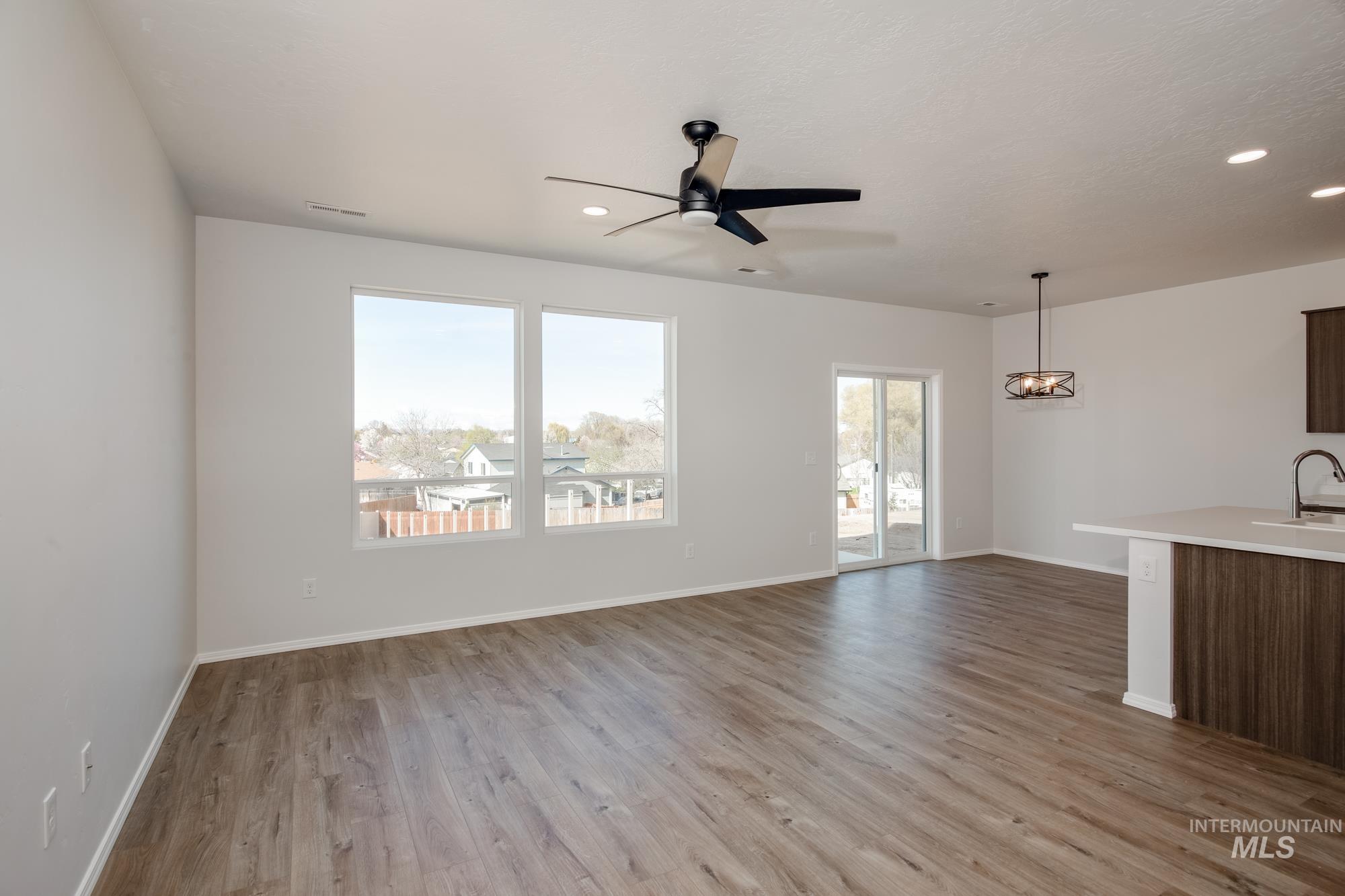 Unfurnished living room featuring light wood-style flooring, ceiling fan, recessed lighting, and a chandelier