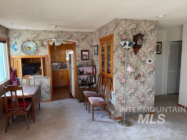 Sitting room with a textured ceiling, wallpapered walls, ceiling fan, and carpet flooring
