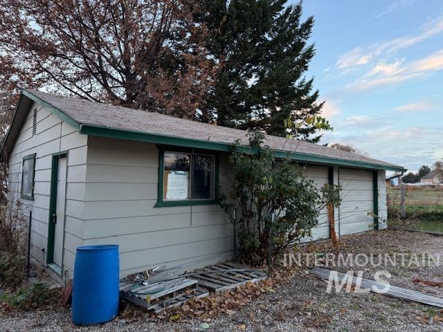 View of side of home featuring a garage and roof with shingles