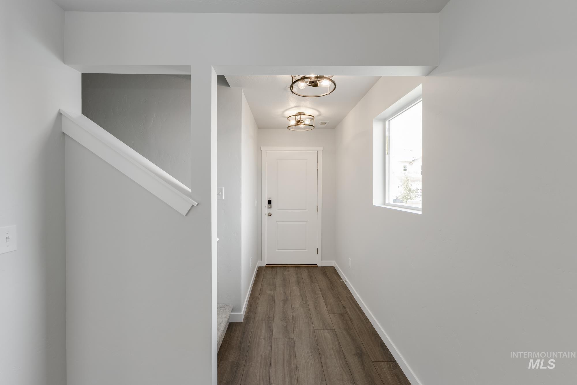 Corridor featuring dark wood-type flooring and a chandelier