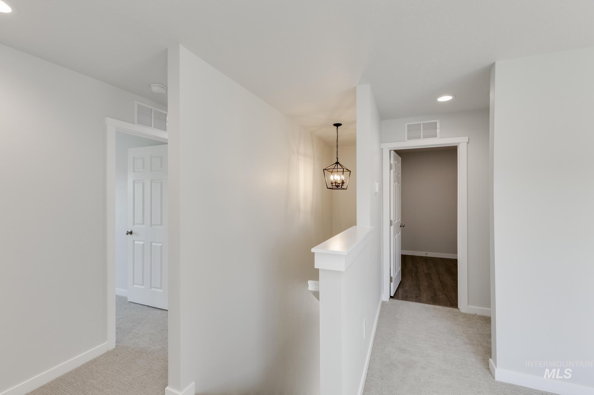 Corridor with an upstairs landing, recessed lighting, and light colored carpet