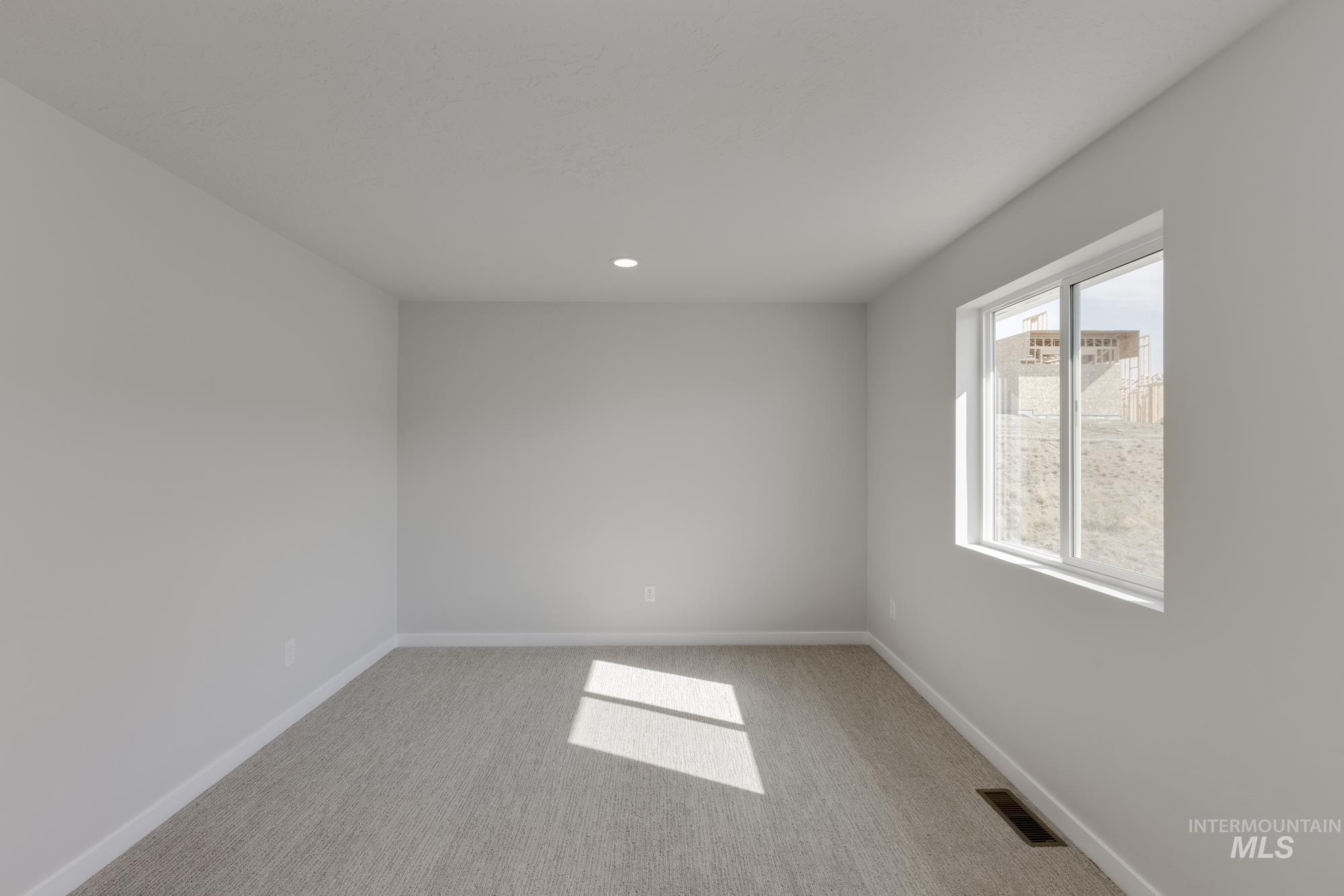 Empty room with light carpet and recessed lighting