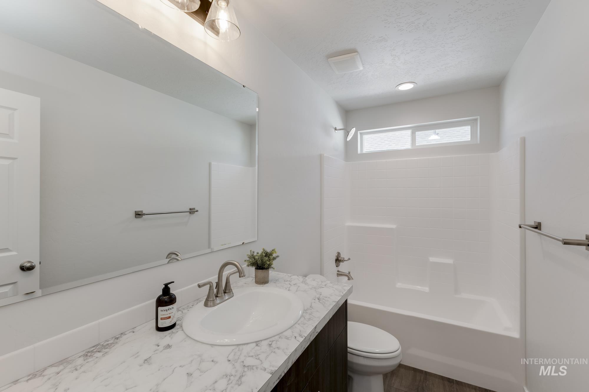 Full bathroom featuring vanity, shower / bath combination, a textured ceiling, and dark wood finished floors