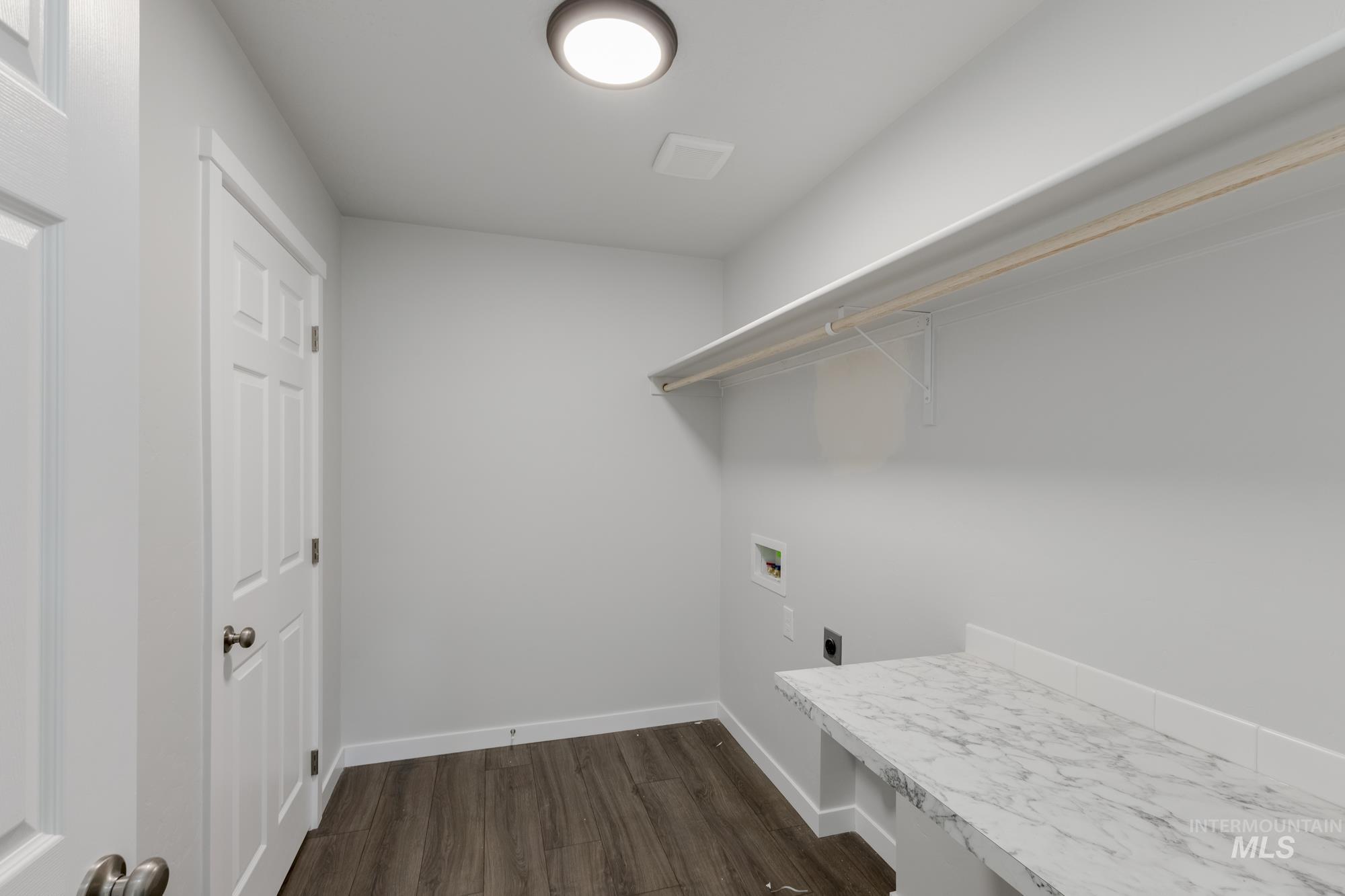 Laundry area with dark wood finished floors, washer hookup, and electric dryer hookup