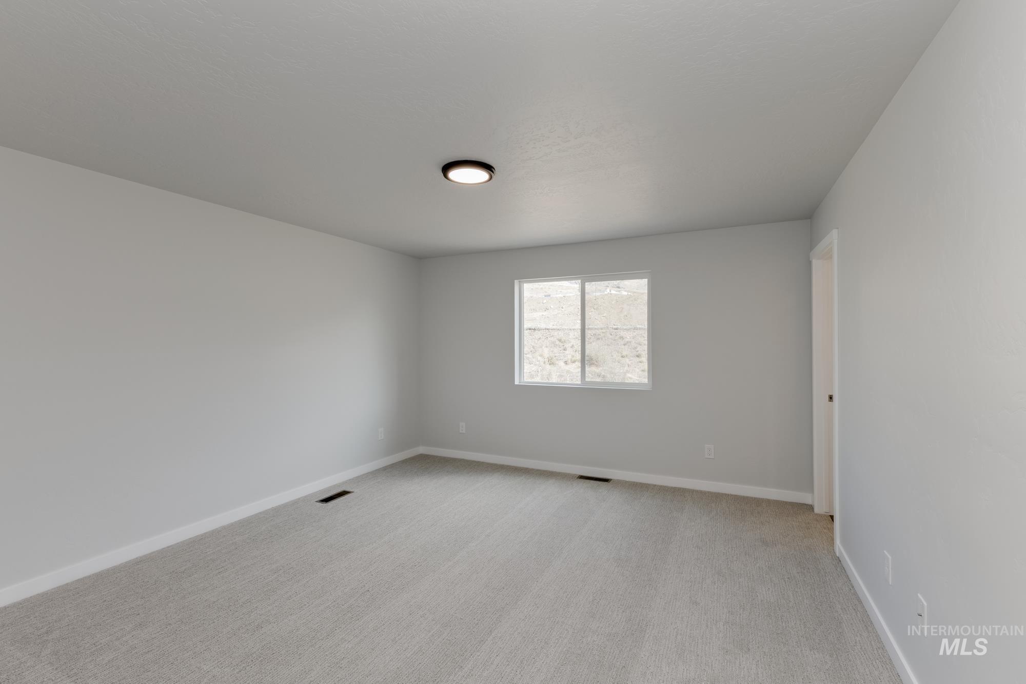 Spare room with light colored carpet and baseboards