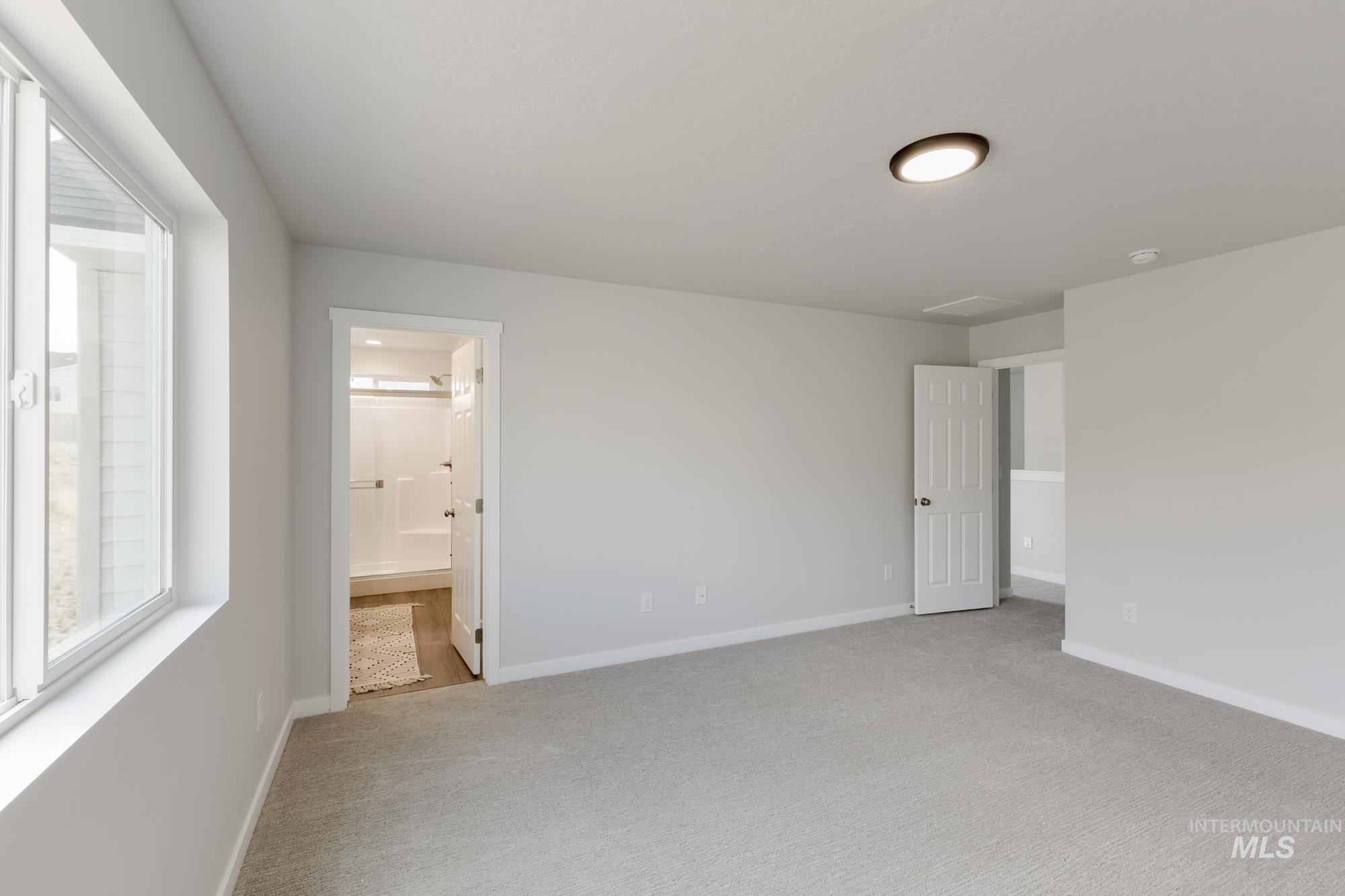 Unfurnished bedroom with light carpet and ensuite bath
