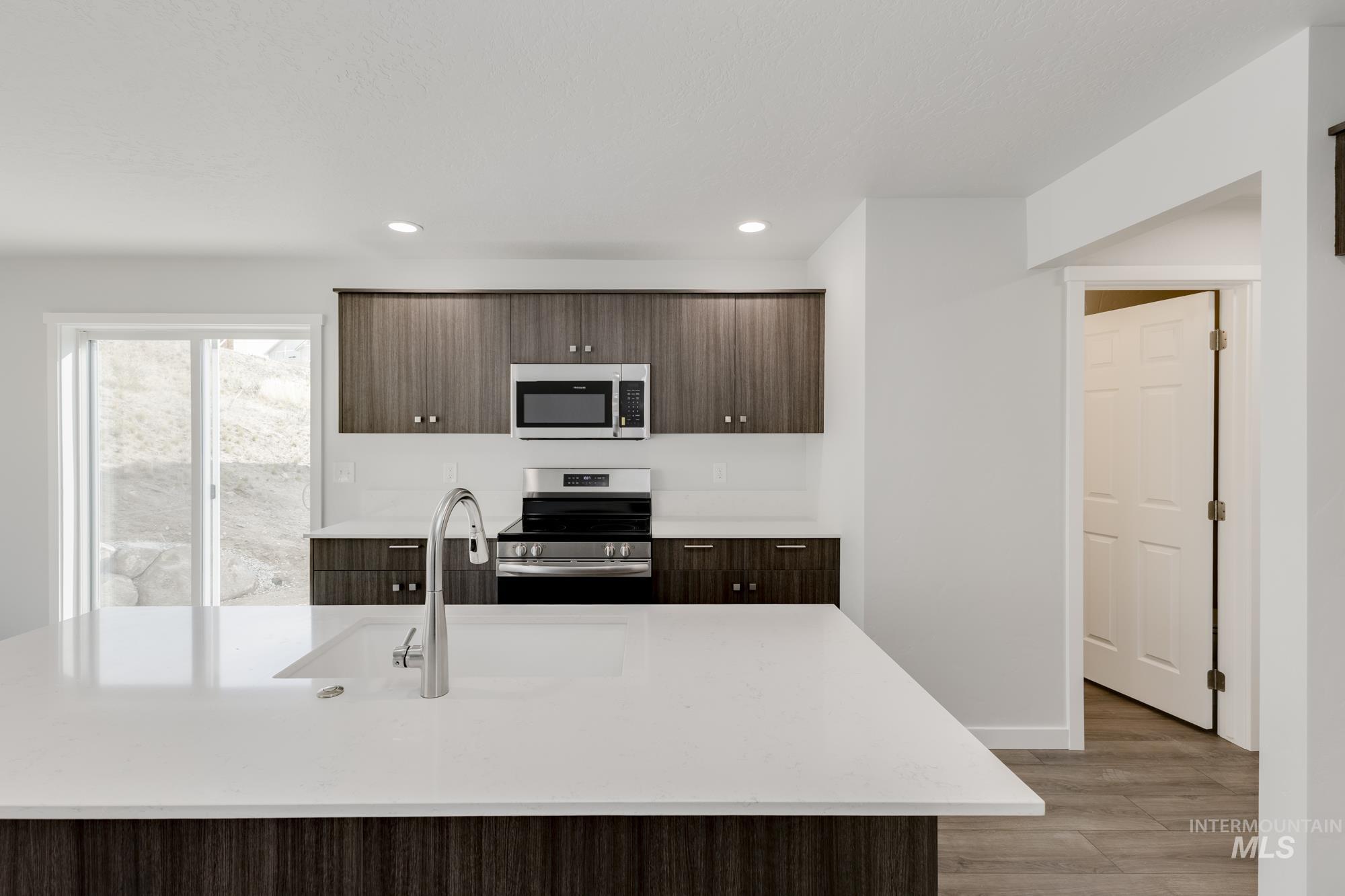 Kitchen featuring dark brown cabinetry, stainless steel appliances, a center island with sink, modern cabinets, and recessed lighting