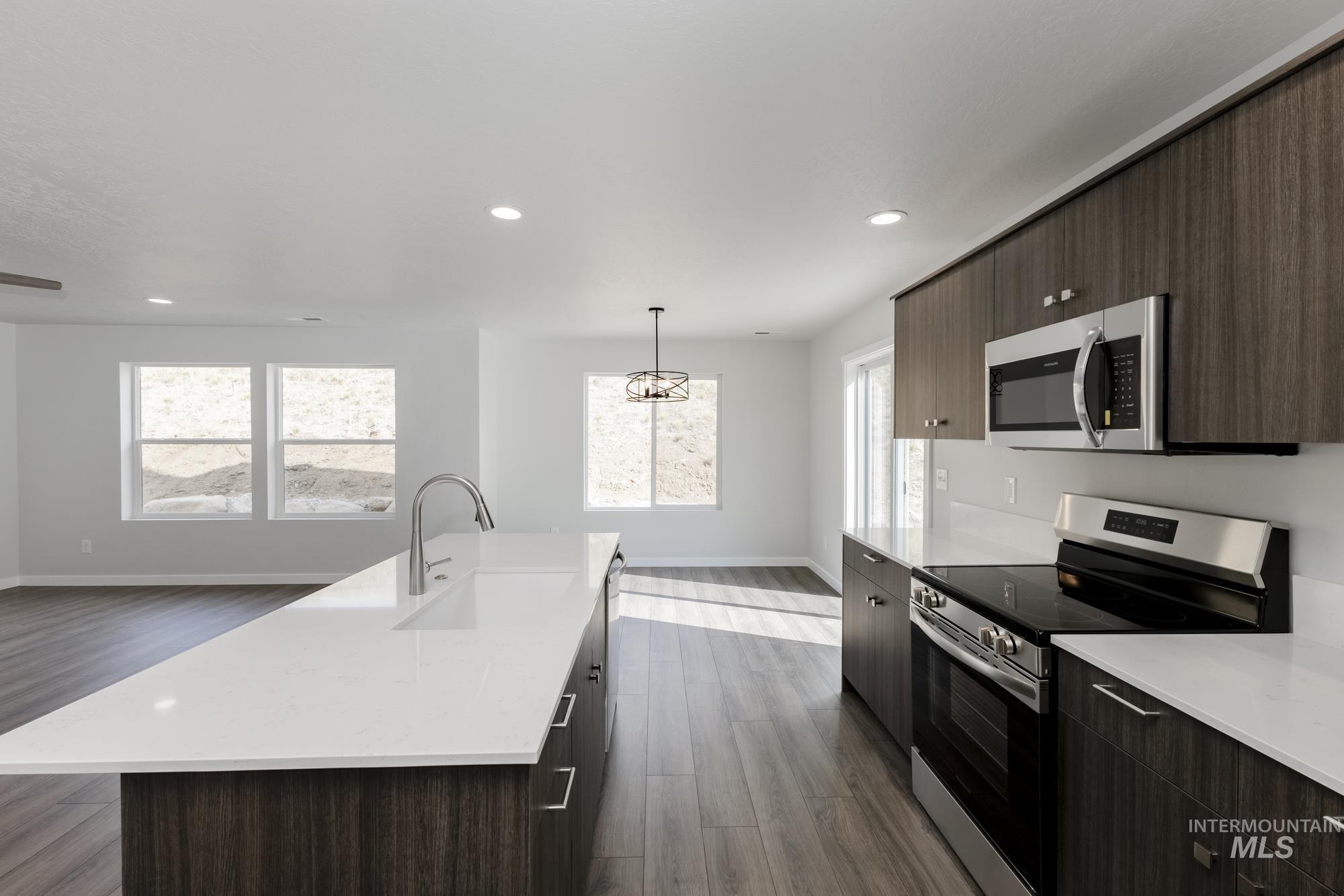 Kitchen with appliances with stainless steel finishes, dark brown cabinetry, pendant lighting, modern cabinets, and recessed lighting