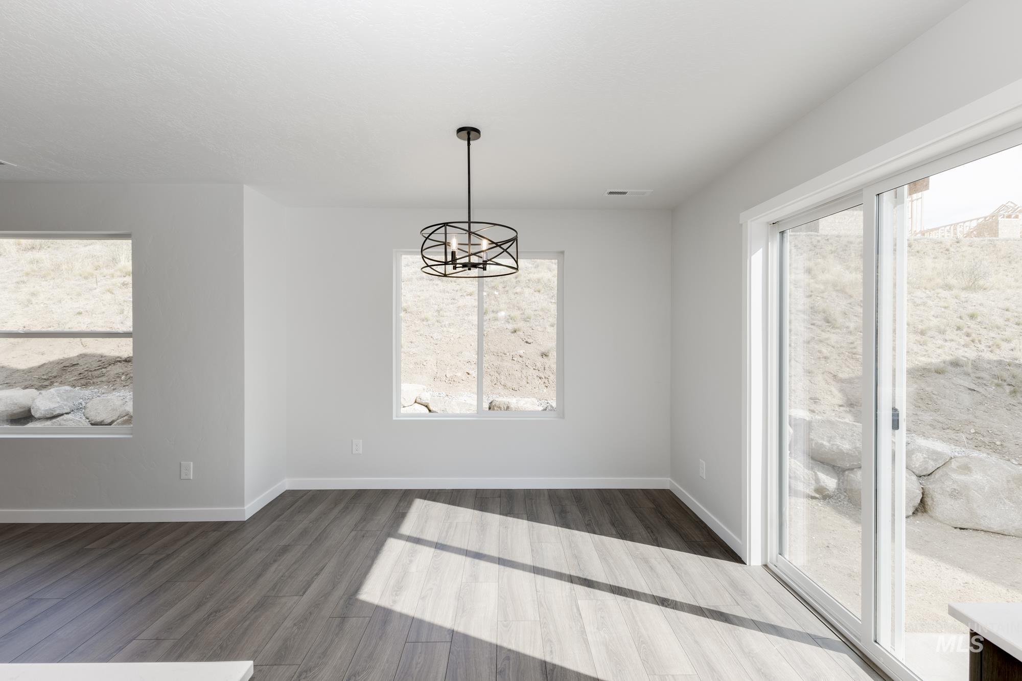 Unfurnished dining area featuring dark wood finished floors and a chandelier