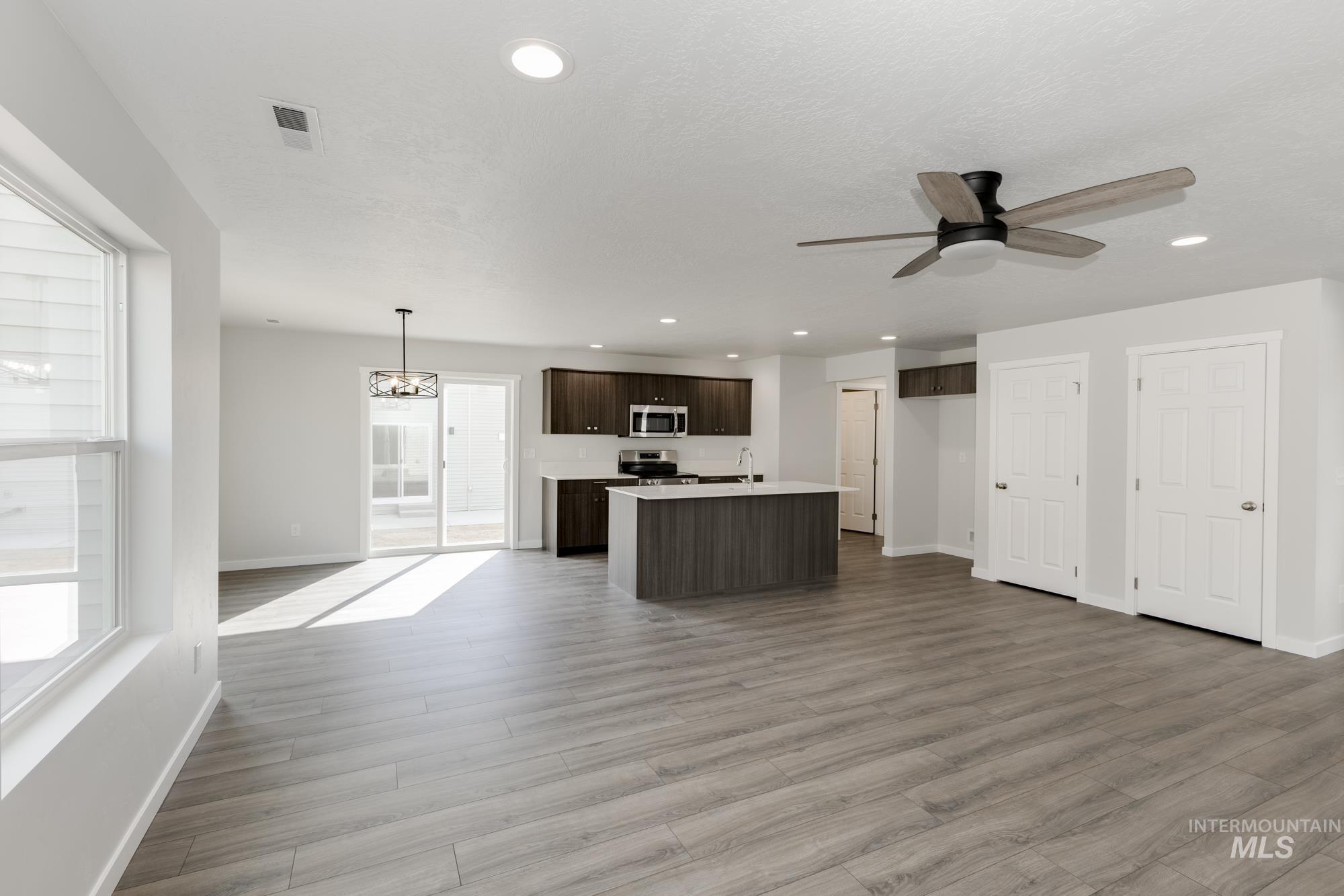 Kitchen with open floor plan, light countertops, light wood-type flooring, dark brown cabinets, and recessed lighting
