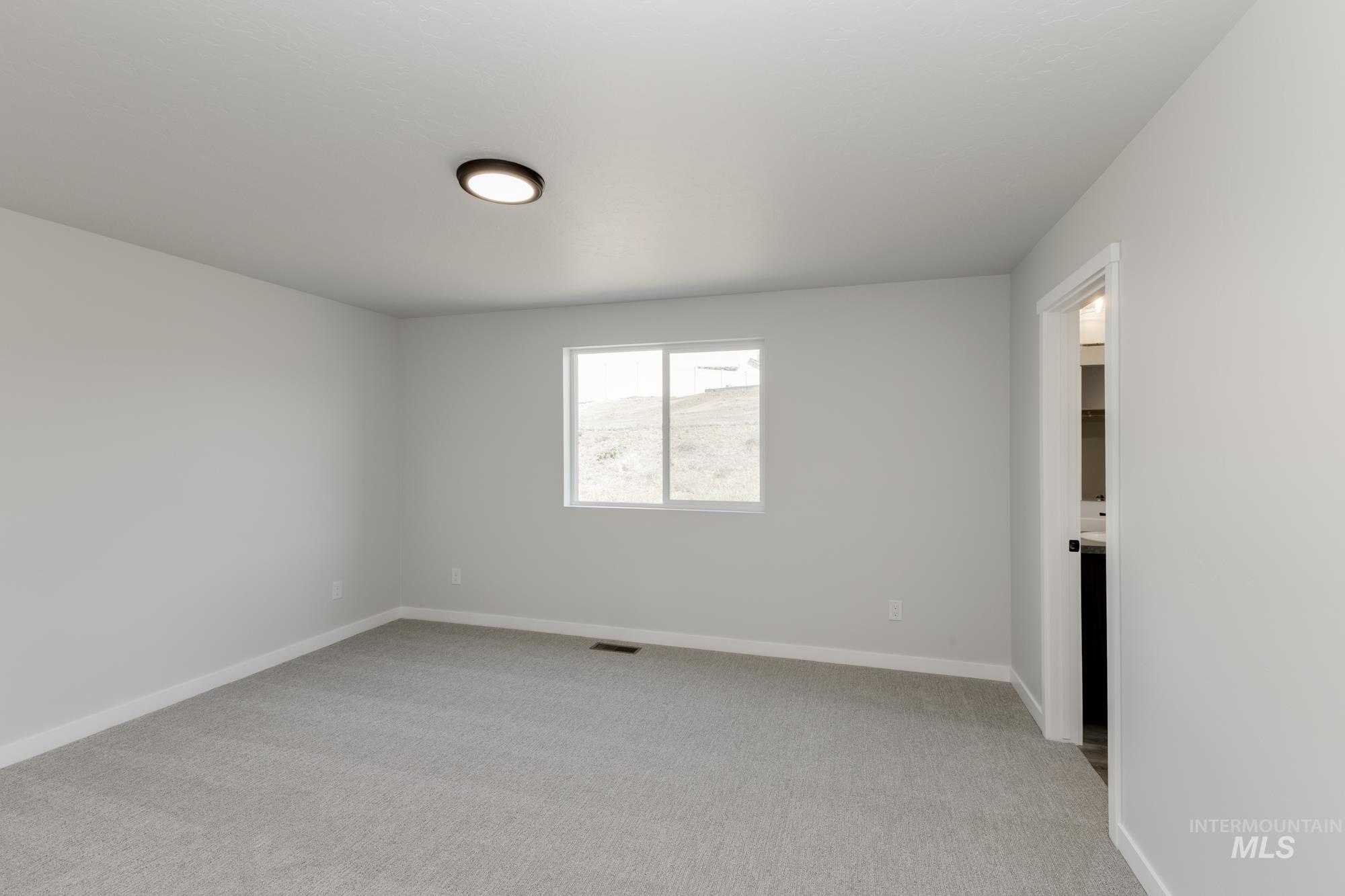 Spare room featuring light colored carpet and baseboards