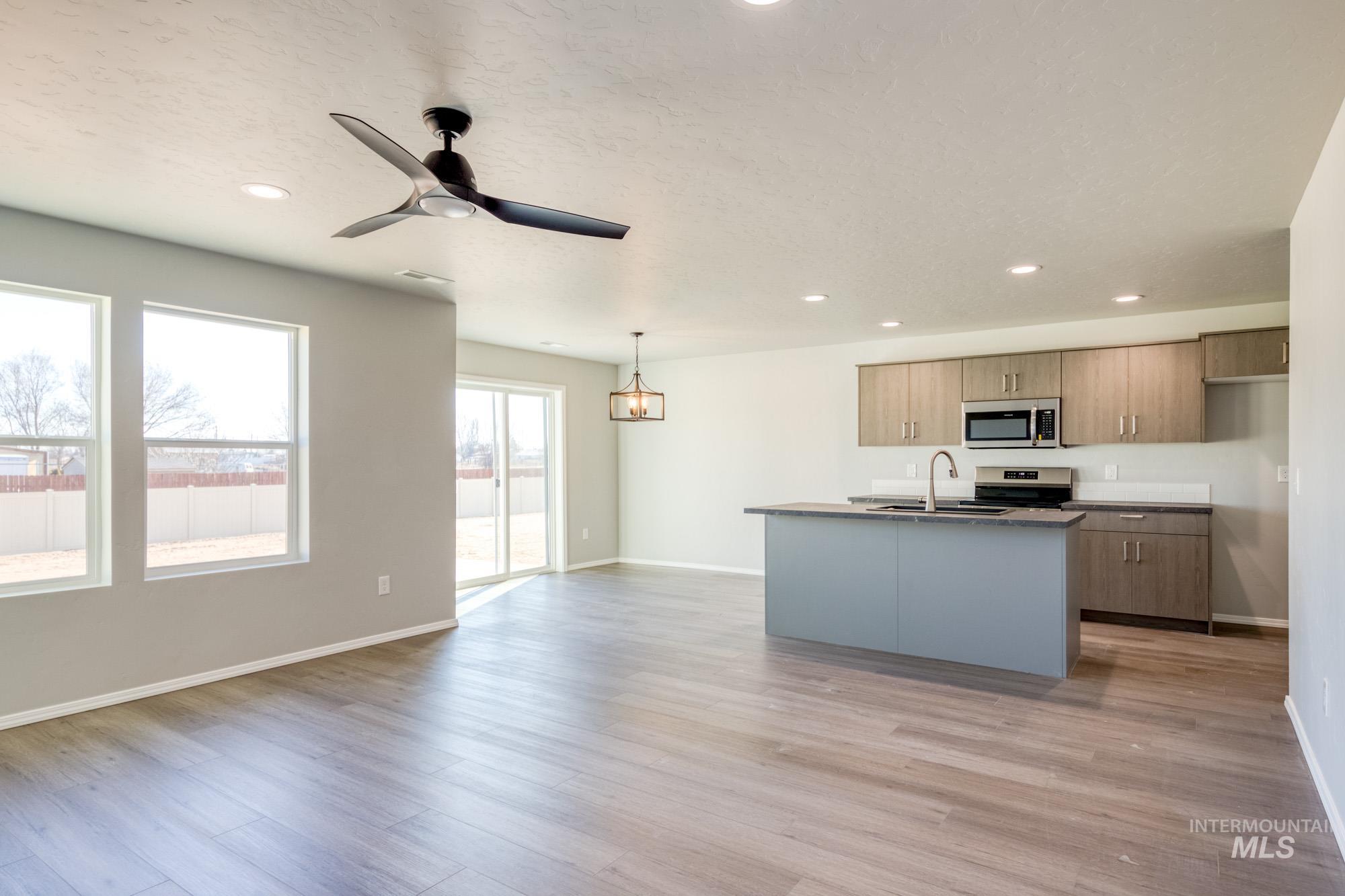 Kitchen with a ceiling fan, open floor plan, a center island with sink, light wood-style flooring, and recessed lighting