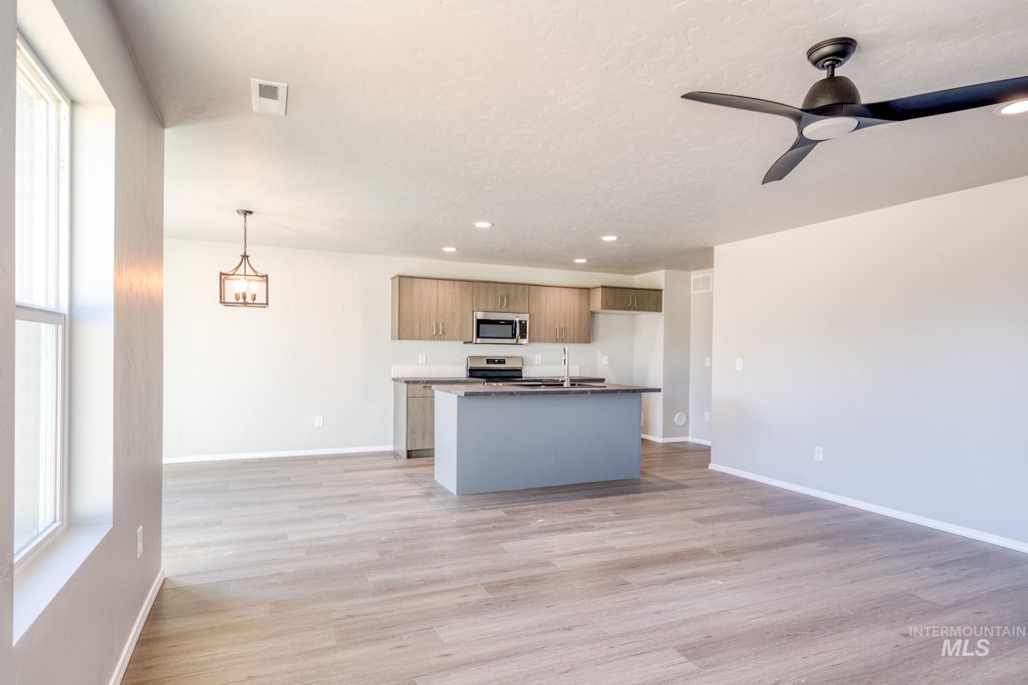 Kitchen with open floor plan, a kitchen island with sink, pendant lighting, recessed lighting, and light wood-style floors