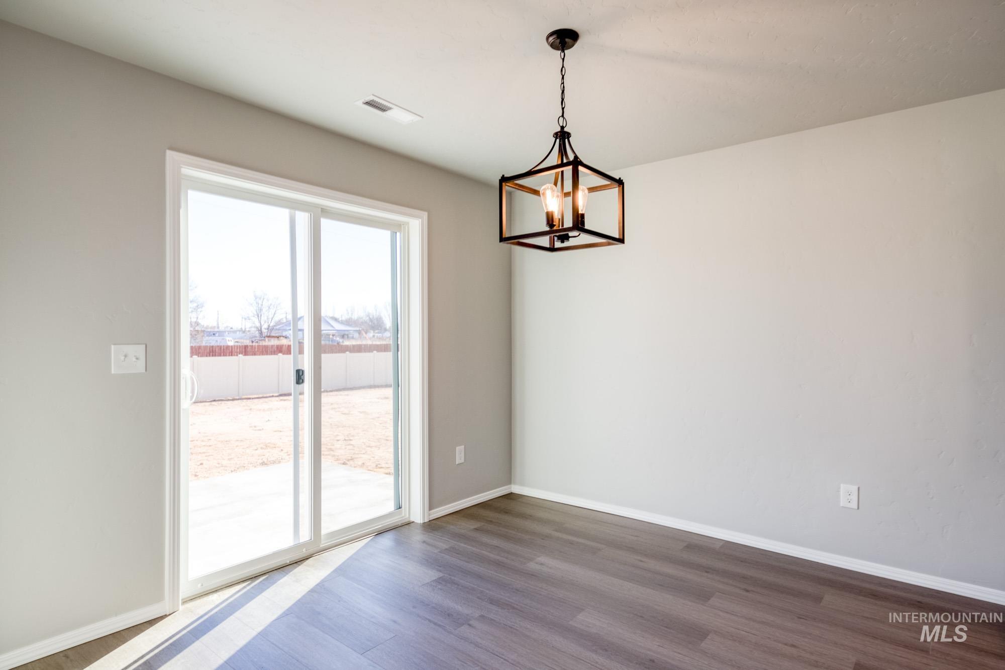 Unfurnished dining area featuring dark wood-style floors and a chandelier