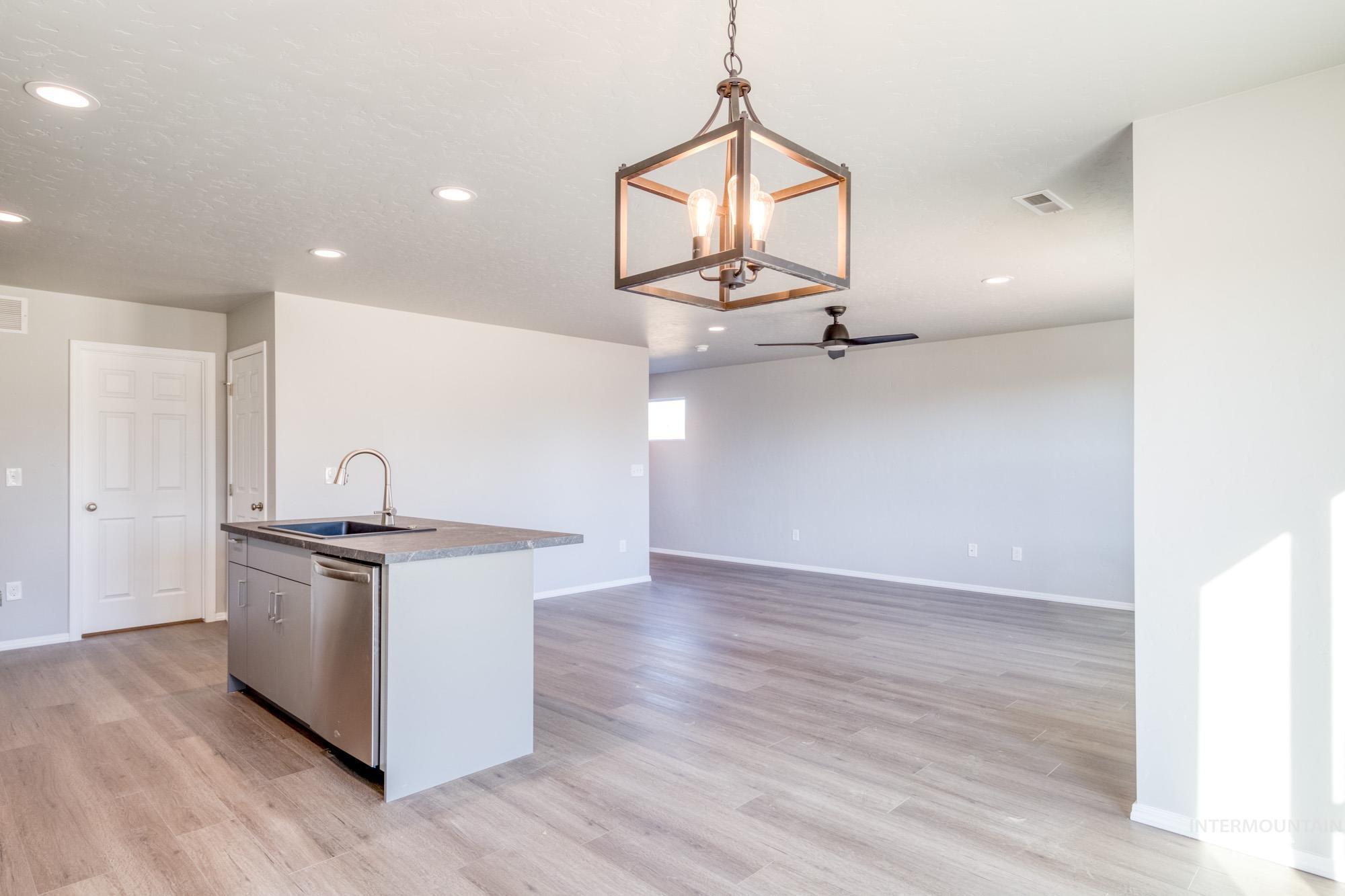 Kitchen with an island with sink, decorative light fixtures, open floor plan, recessed lighting, and light wood finished floors