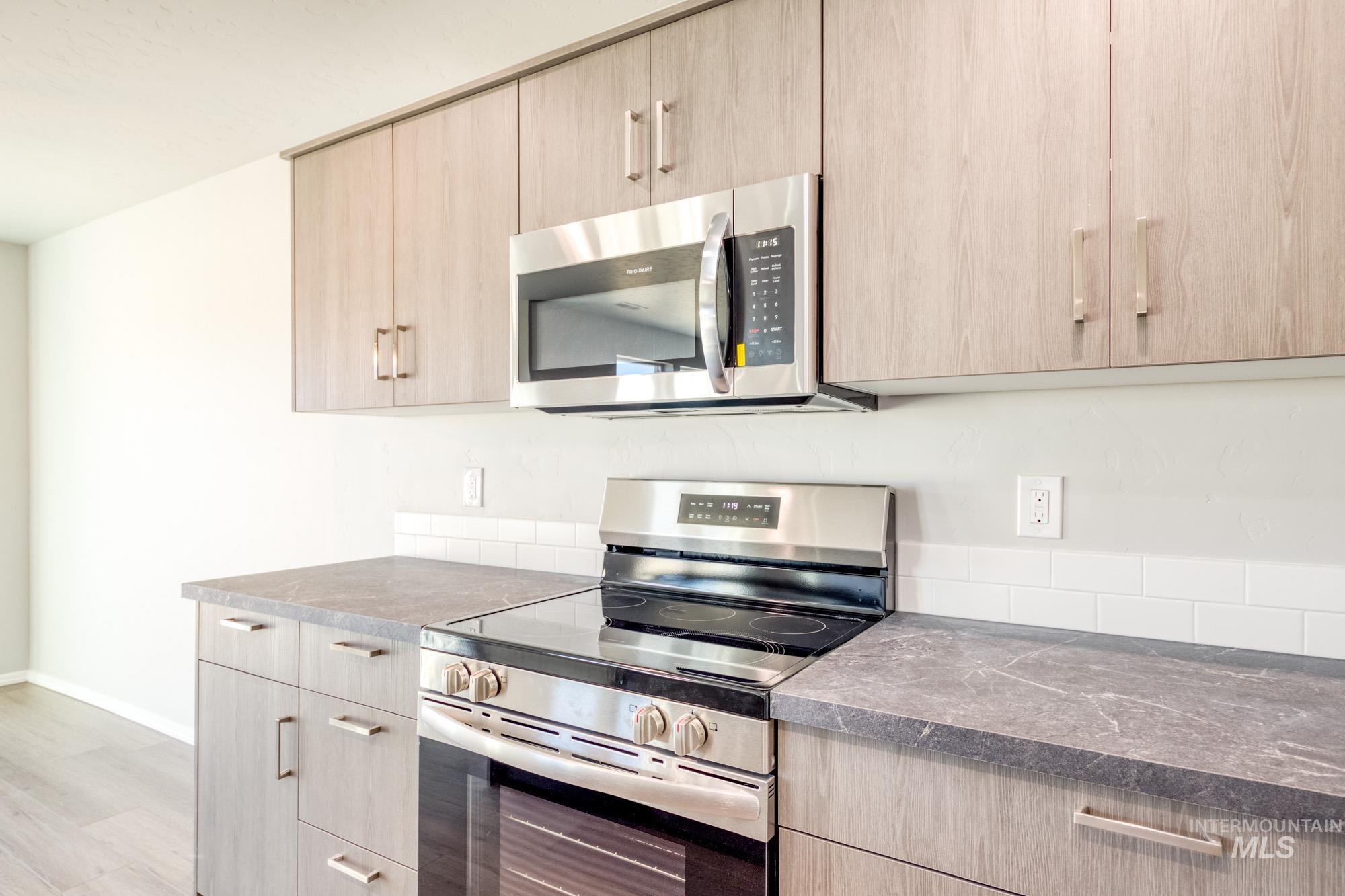 Kitchen with light brown cabinets, appliances with stainless steel finishes, and modern cabinets