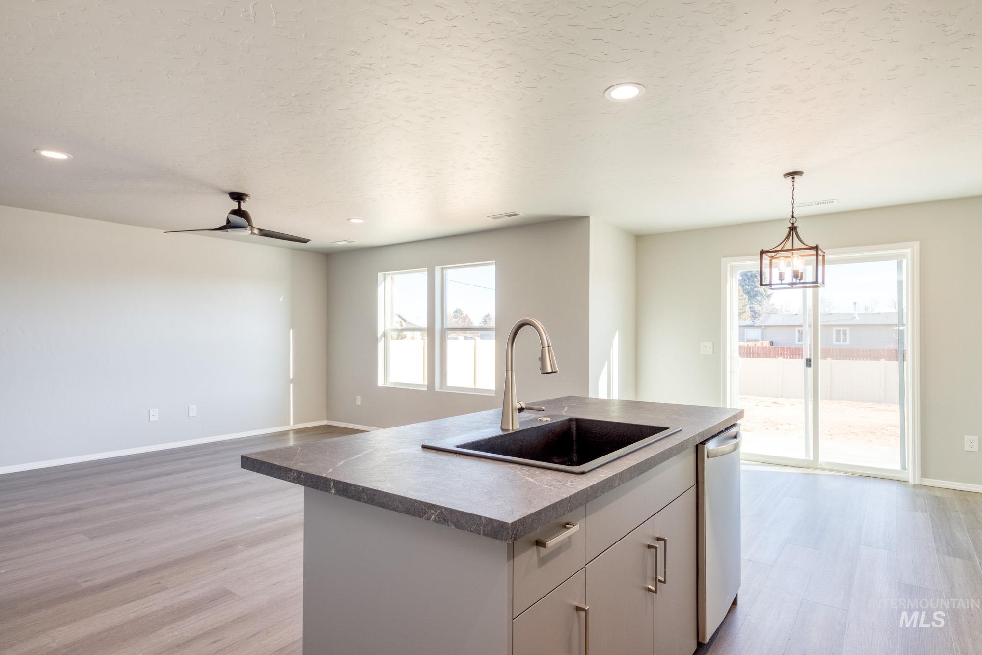 Kitchen with open floor plan, light wood finished floors, pendant lighting, a kitchen island with sink, and a textured ceiling