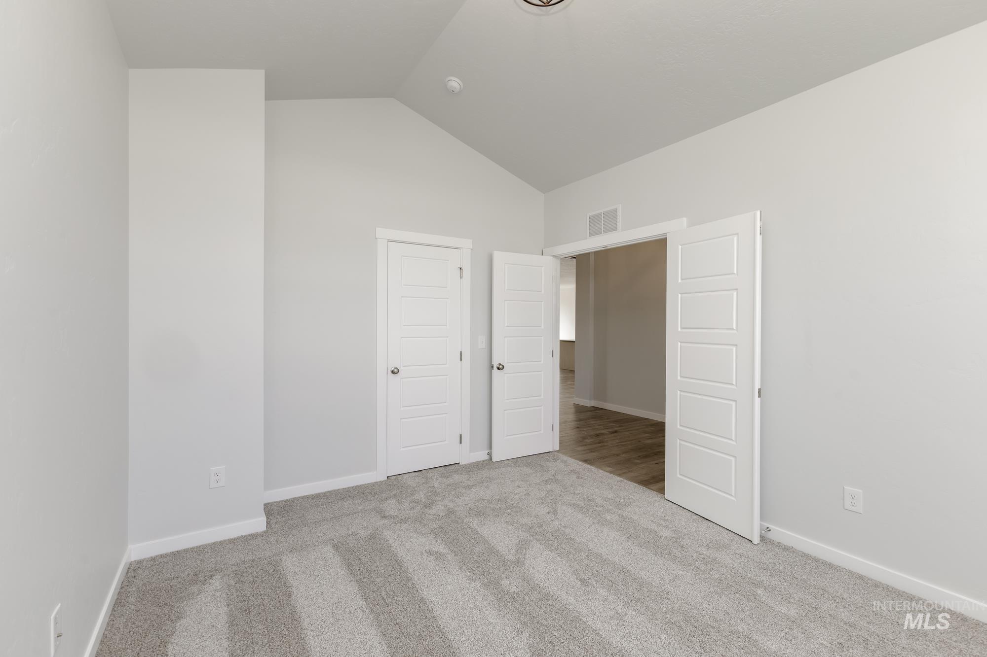 Unfurnished bedroom with lofted ceiling, light colored carpet, and a closet