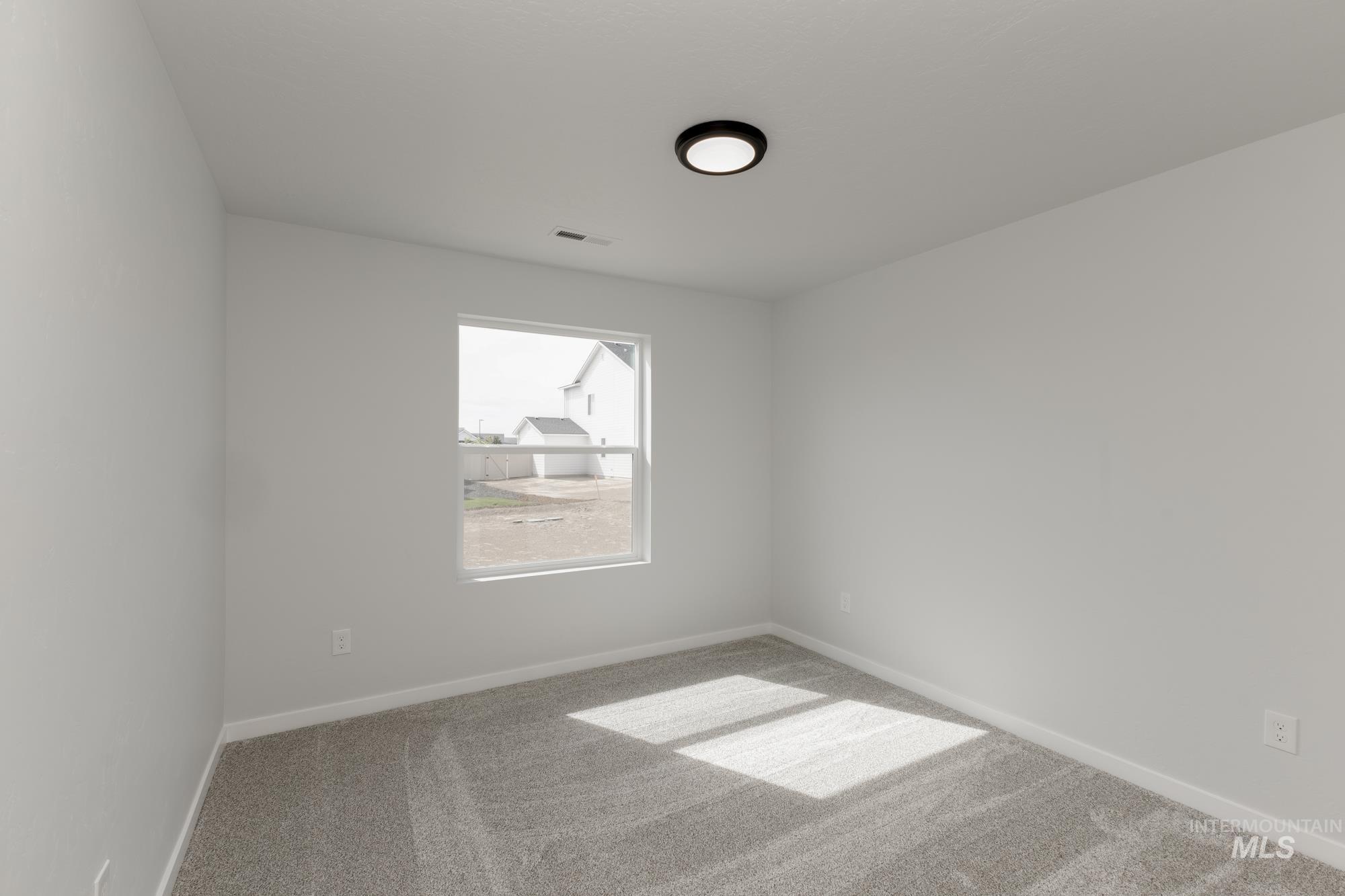 Carpeted spare room featuring baseboards