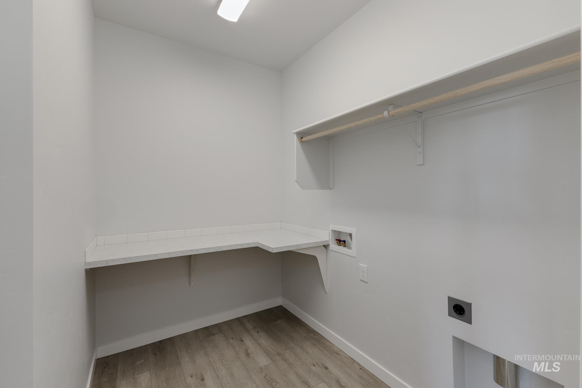 Laundry room featuring light wood-style flooring, hookup for a washing machine, electric dryer hookup, and an office area