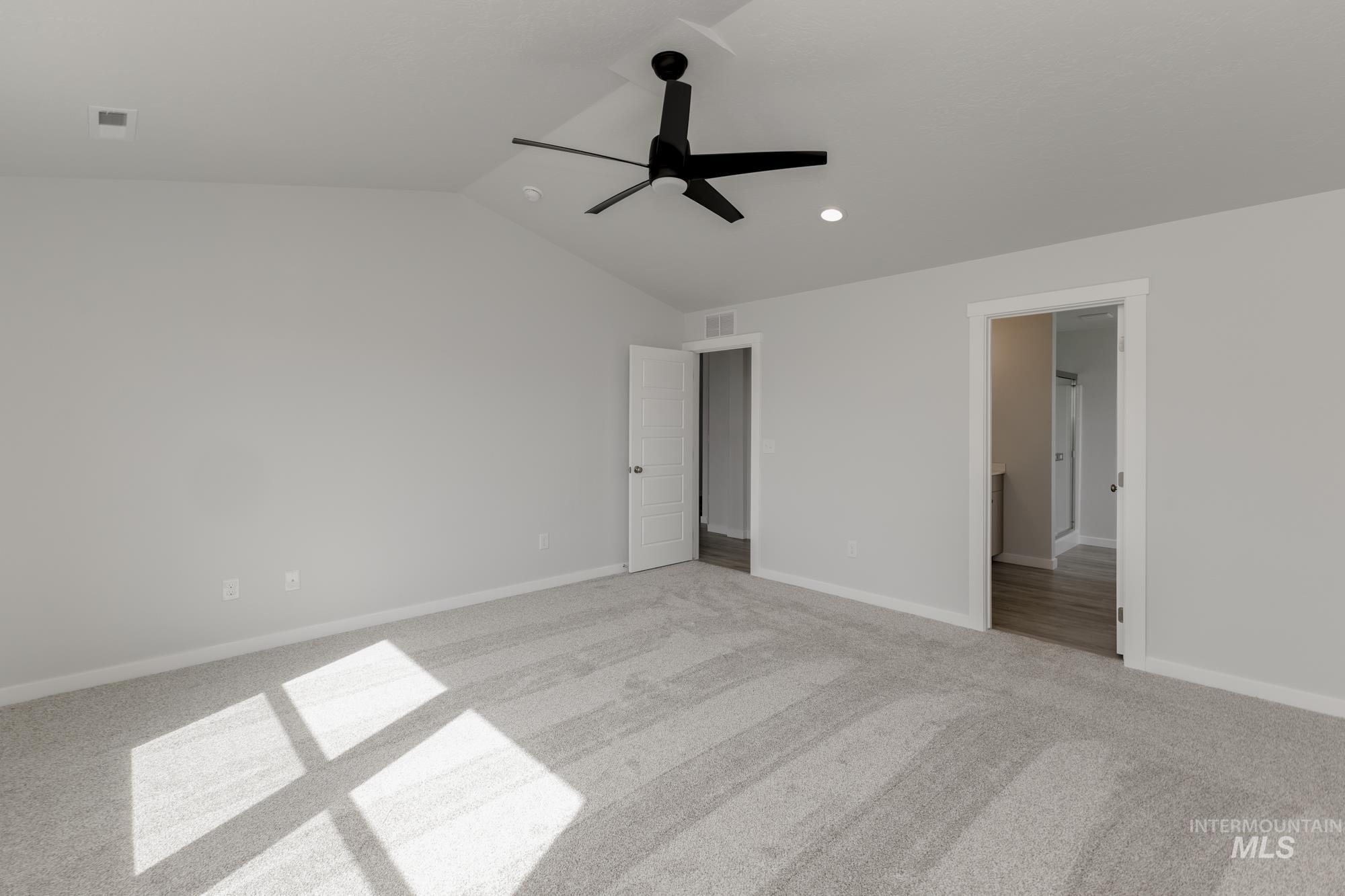Unfurnished bedroom featuring vaulted ceiling, ceiling fan, light carpet, recessed lighting, and ensuite bathroom