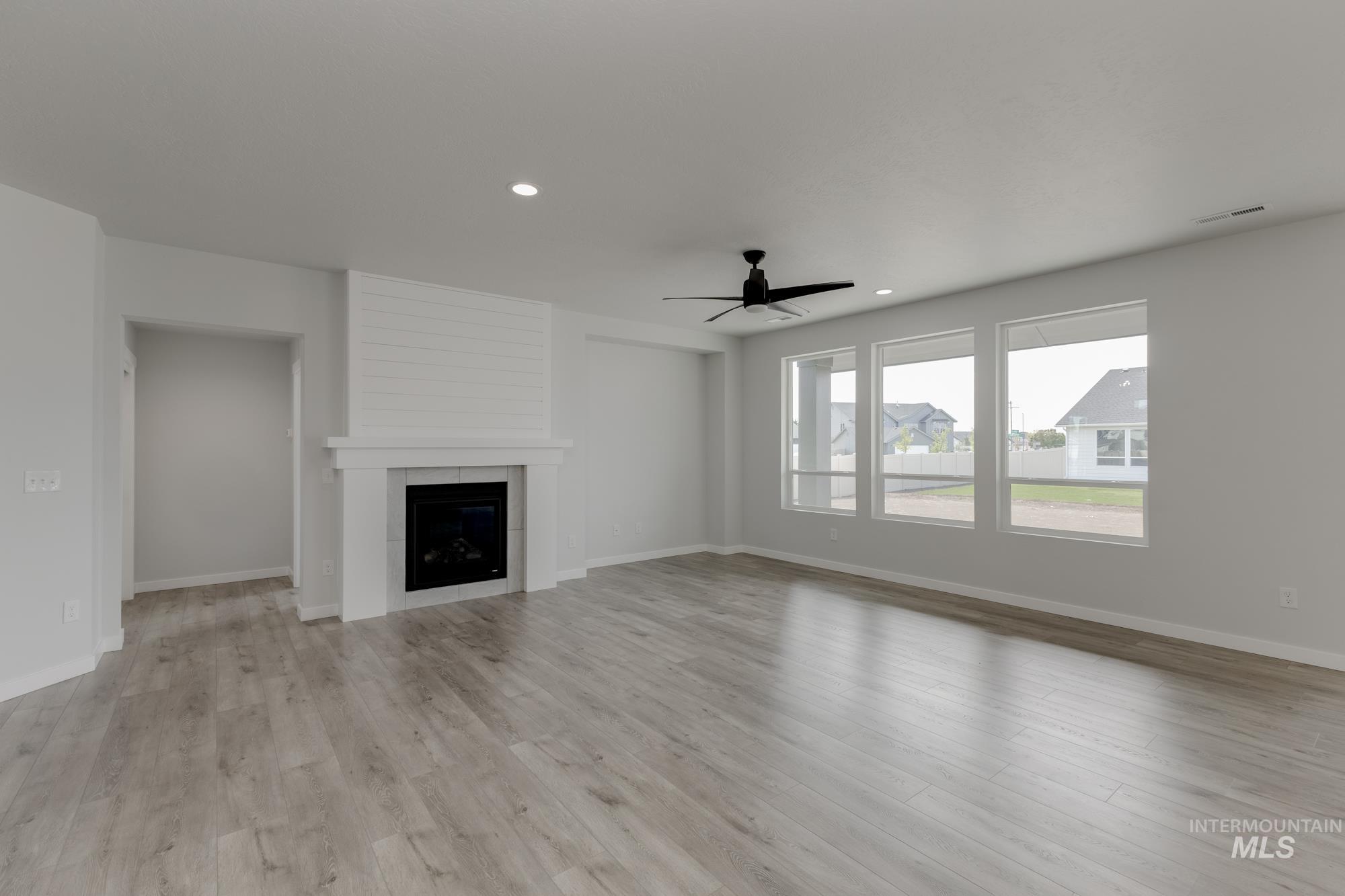 Unfurnished living room with a fireplace, recessed lighting, light wood-type flooring, and a ceiling fan
