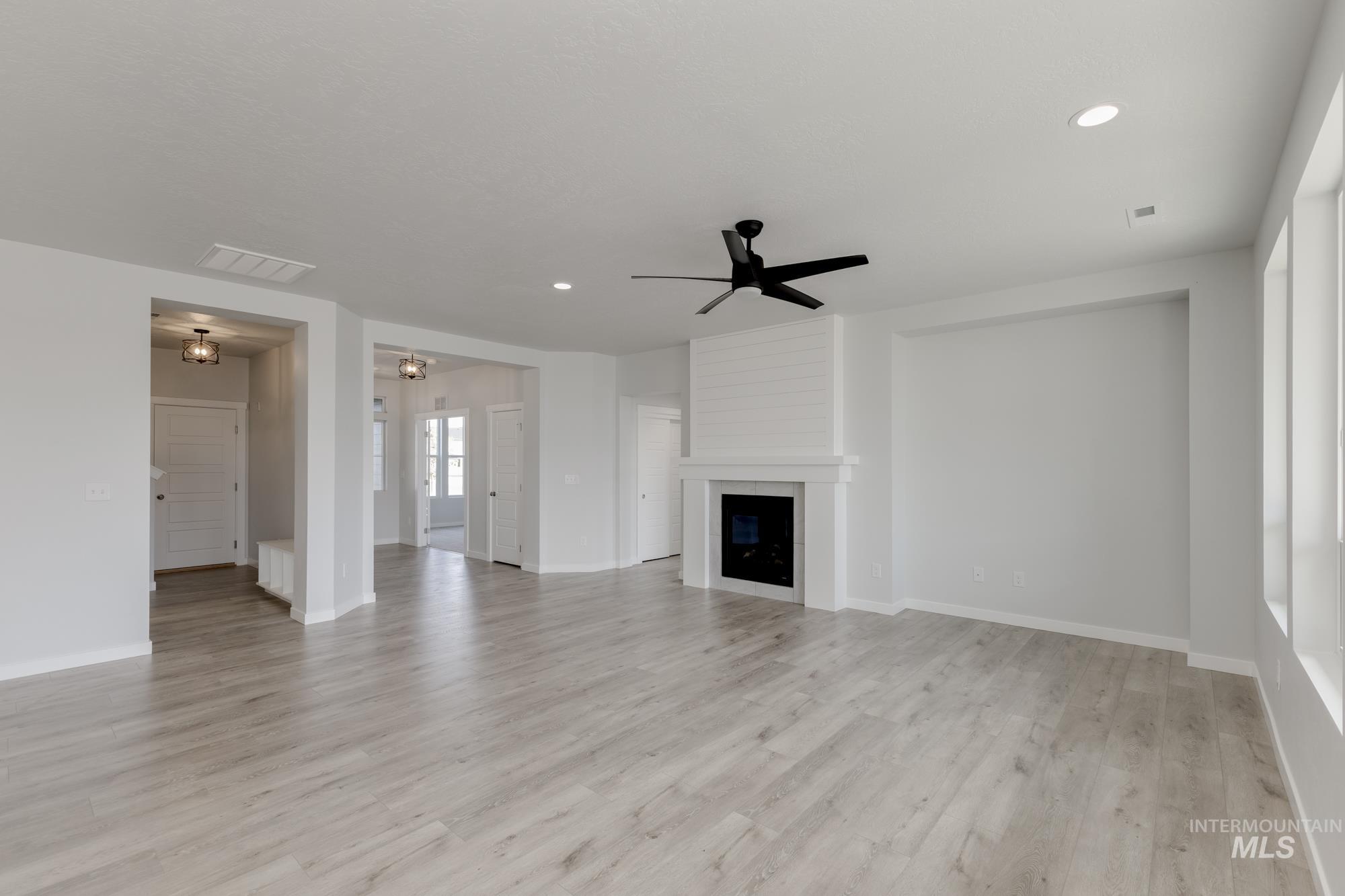 Unfurnished living room with ceiling fan, light wood-type flooring, a large fireplace, and recessed lighting