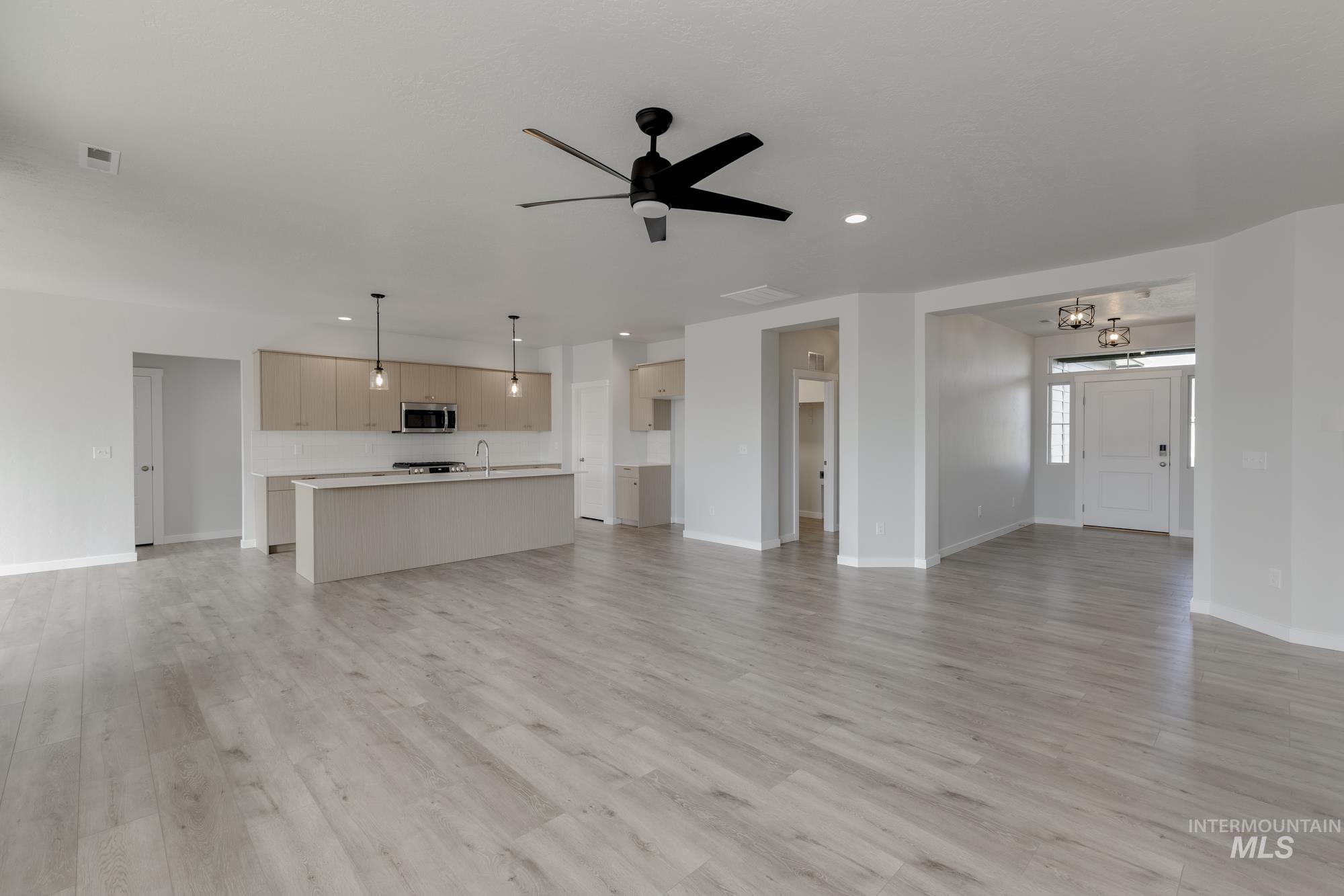 Unfurnished living room with light wood-type flooring, ceiling fan, a chandelier, and recessed lighting