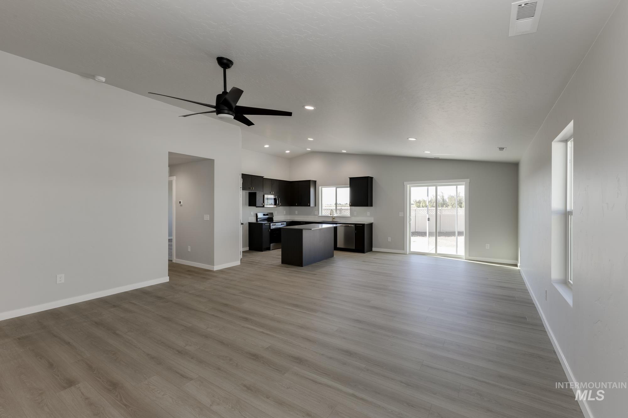 Unfurnished living room with light wood-style flooring, vaulted ceiling, recessed lighting, and a ceiling fan