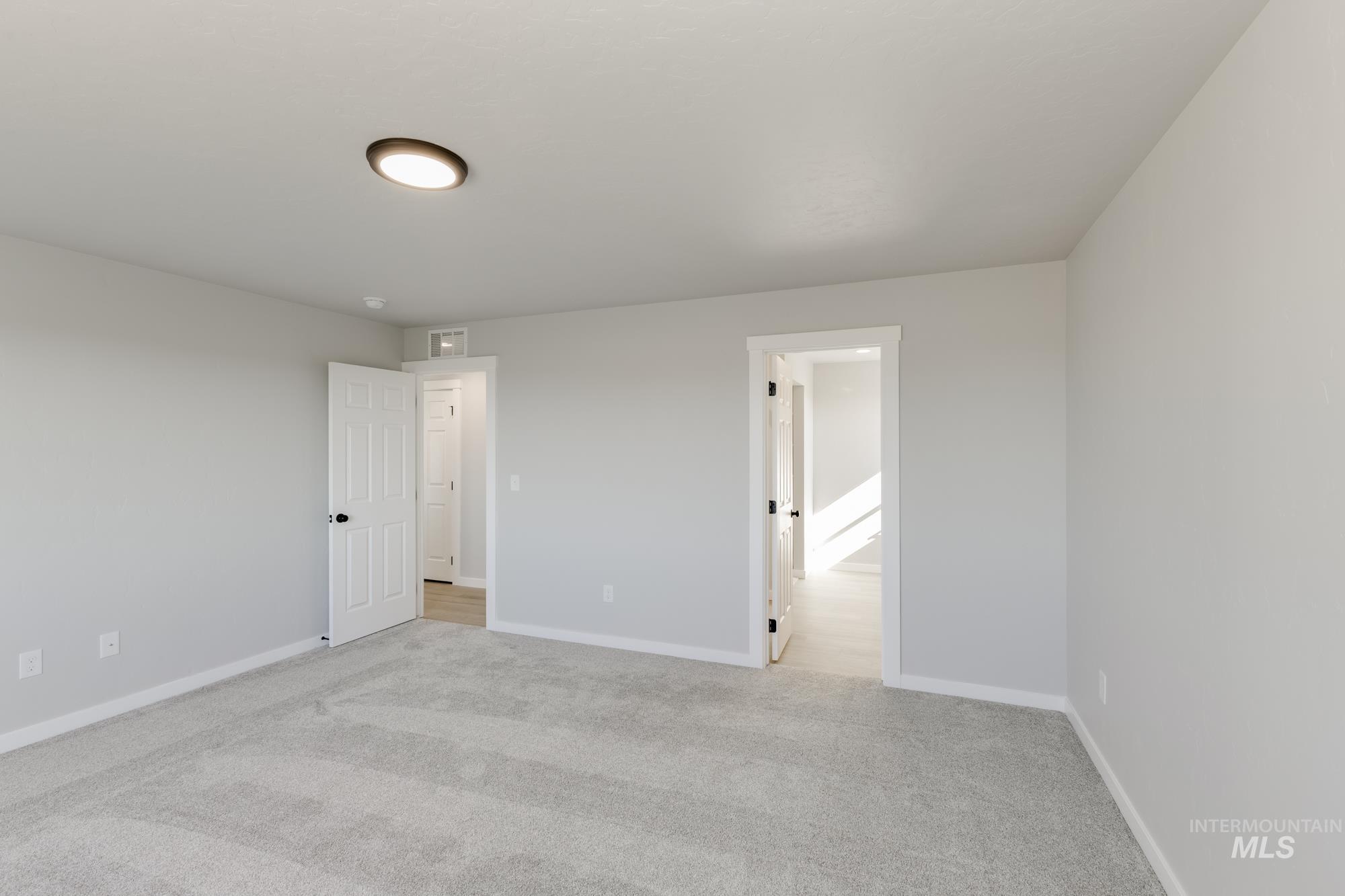 Unfurnished bedroom featuring light colored carpet and ensuite bath