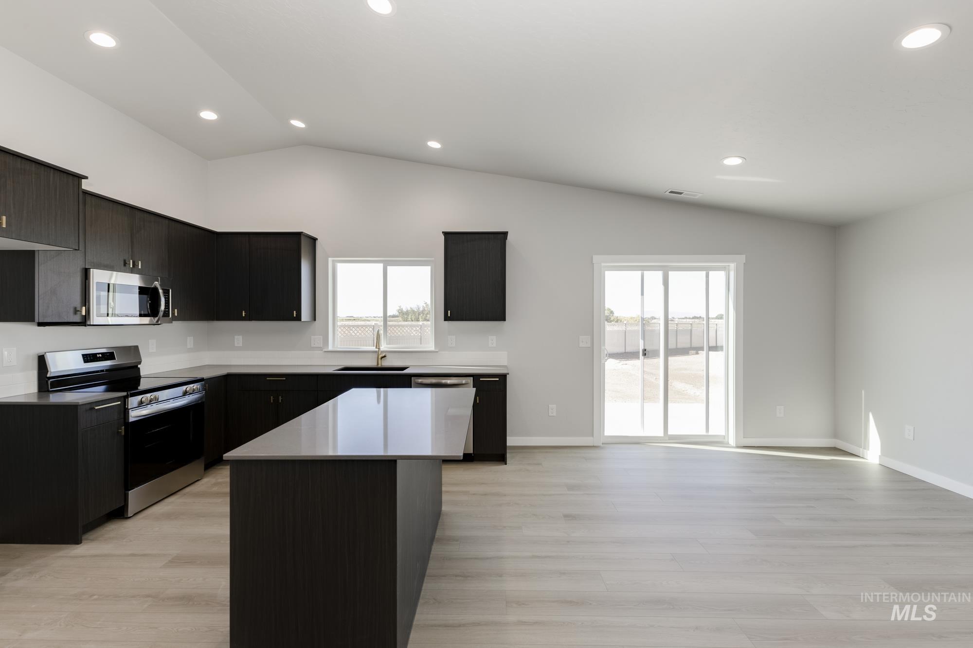 Kitchen with stainless steel appliances, recessed lighting, a center island, healthy amount of natural light, and lofted ceiling