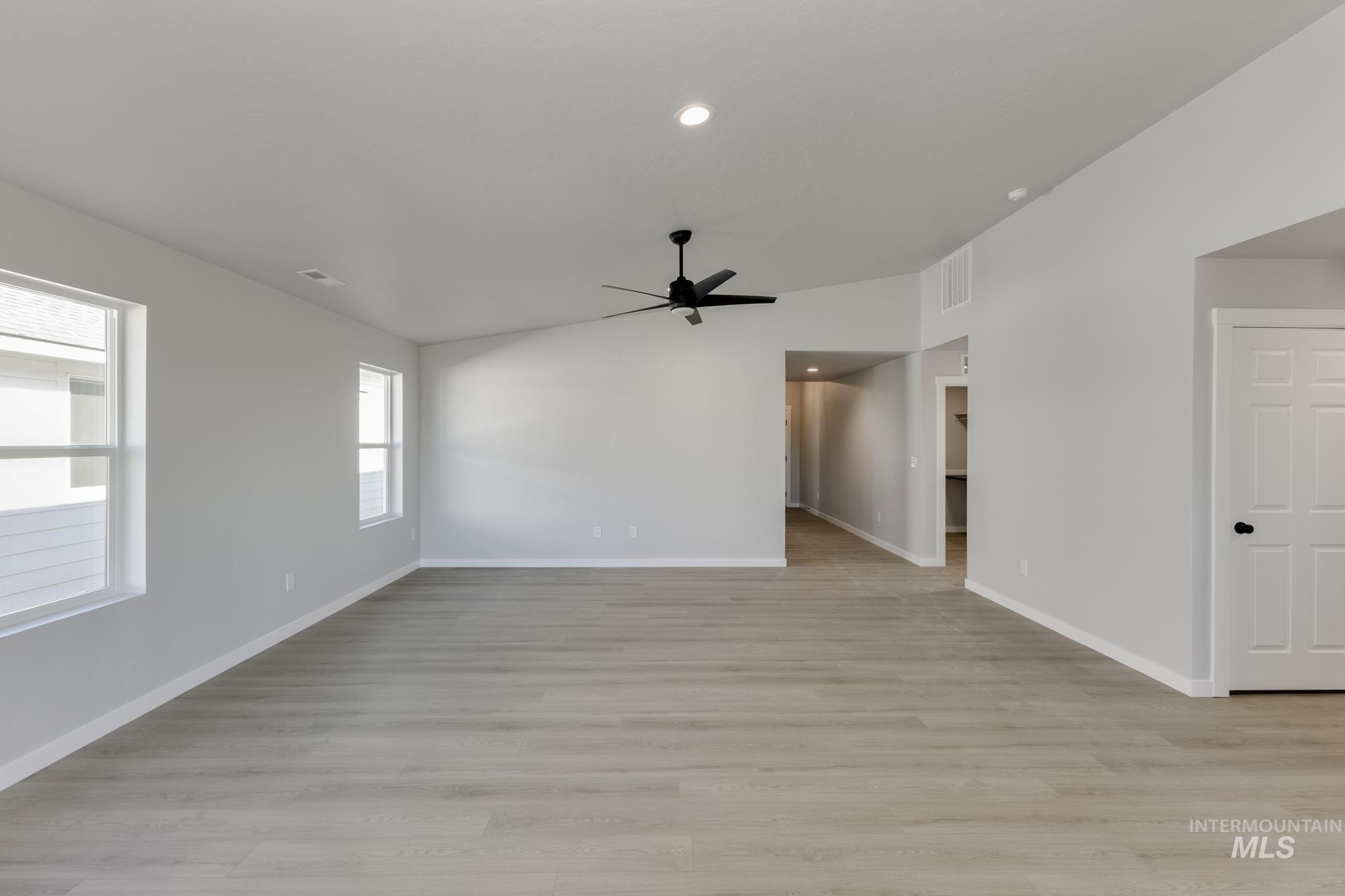Empty room featuring light wood-style flooring, ceiling fan, recessed lighting, and lofted ceiling
