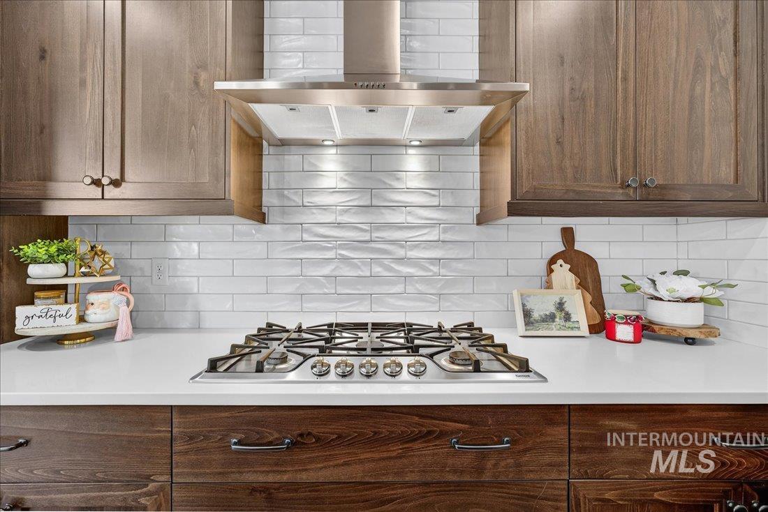 Kitchen featuring range hood, decorative backsplash, and stainless steel gas cooktop