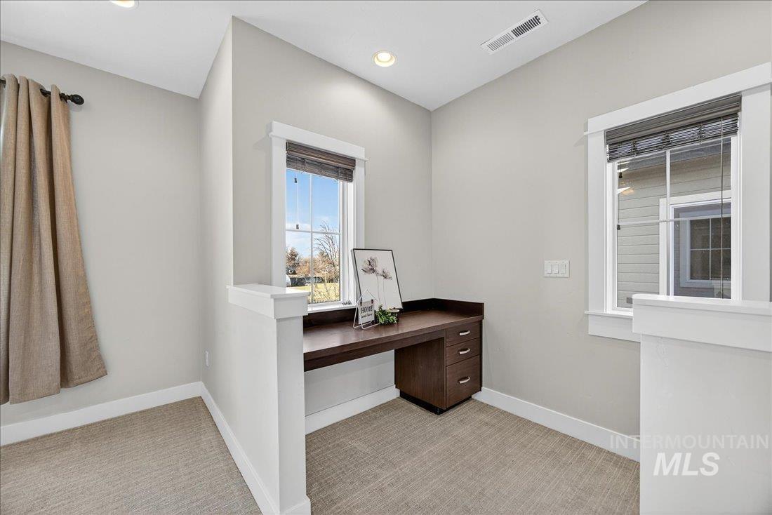 Unfurnished office featuring light colored carpet, built in desk, and recessed lighting