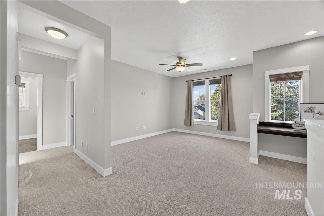 Empty room featuring light colored carpet, a ceiling fan, a textured ceiling, and recessed lighting