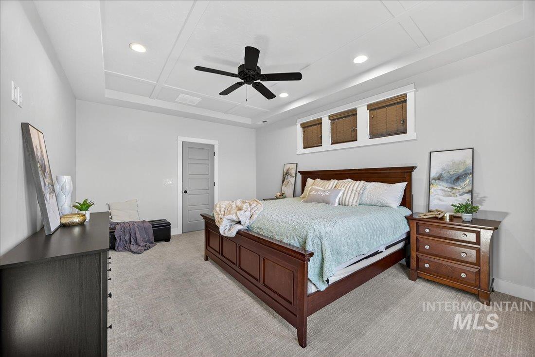Bedroom with light carpet, ceiling fan, a raised ceiling, and recessed lighting