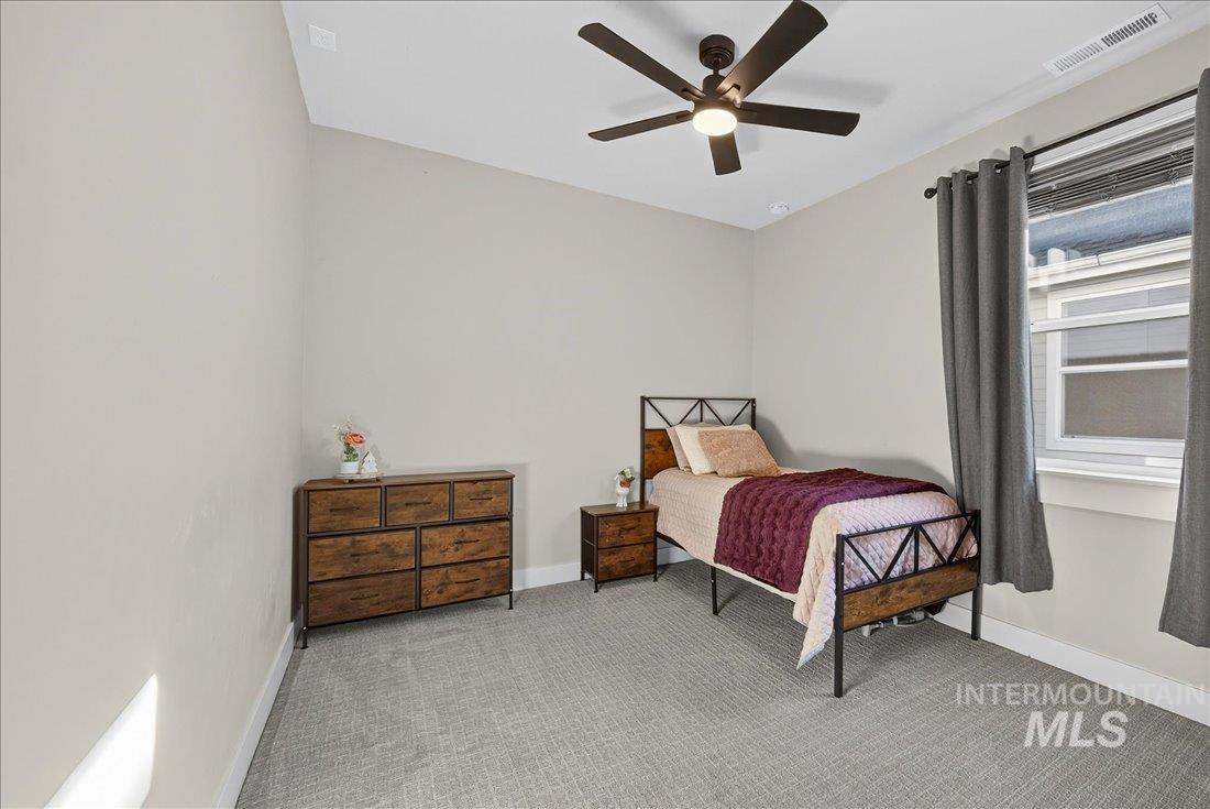 Carpeted bedroom featuring a ceiling fan and baseboards