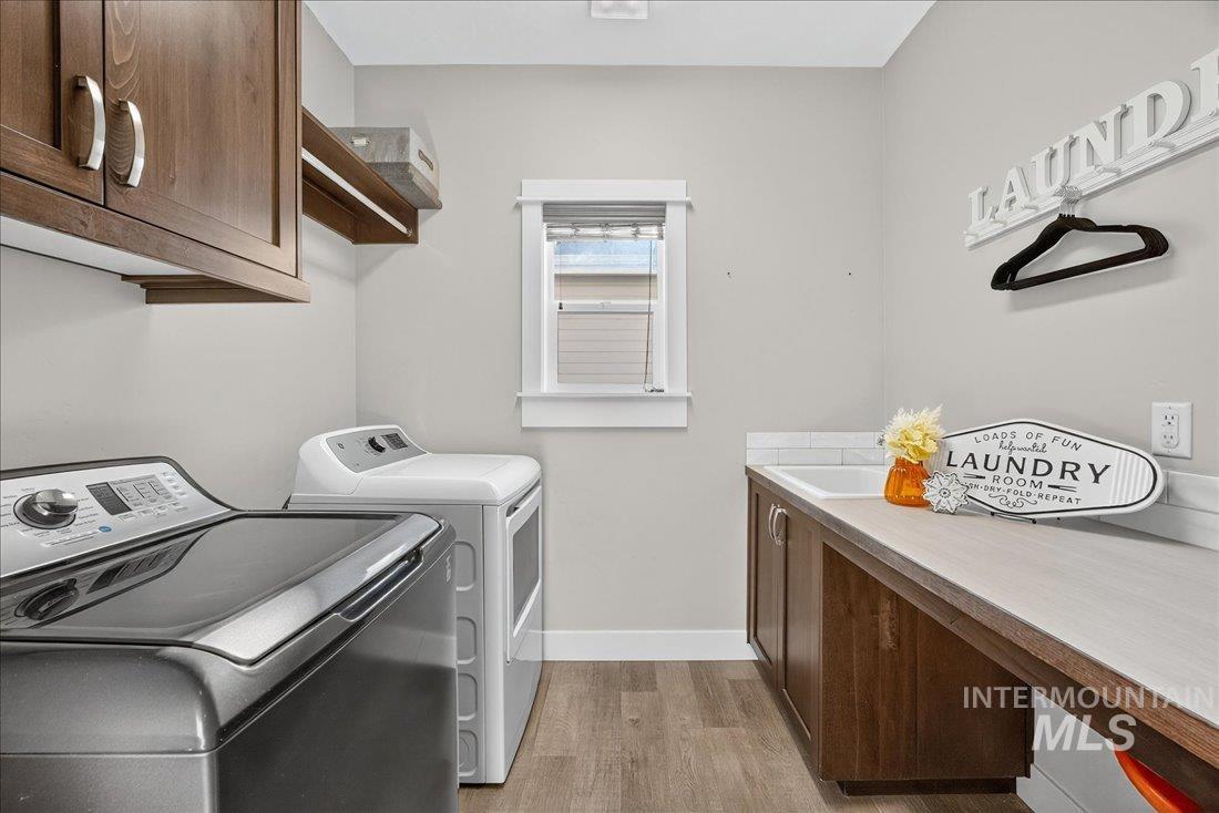 Laundry room with cabinet space, light wood finished floors, and independent washer and dryer