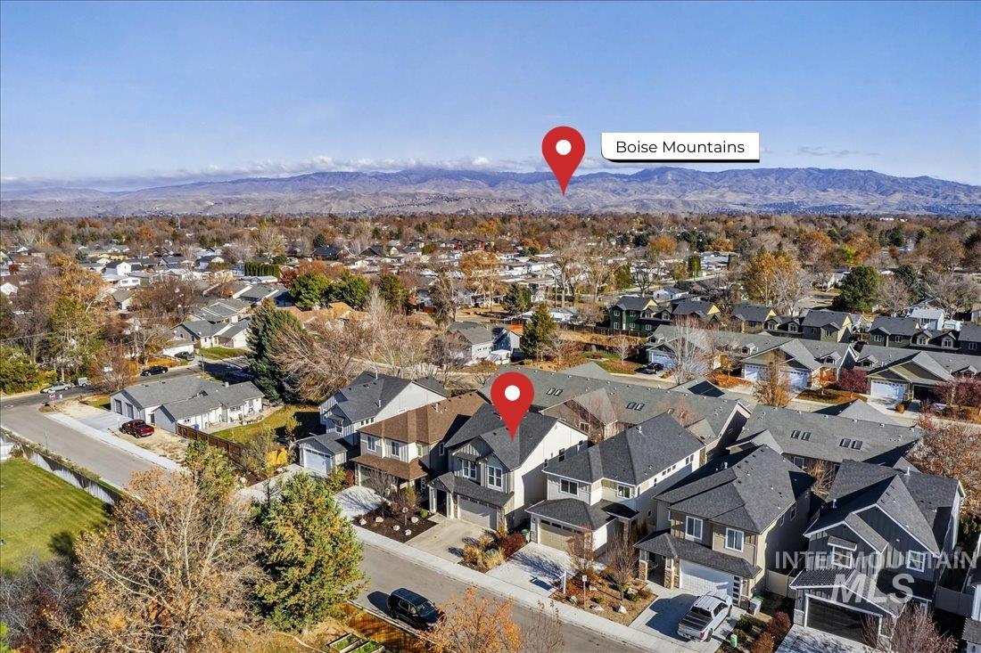 Aerial view of property and surrounding area featuring a mountain backdrop and nearby suburban area