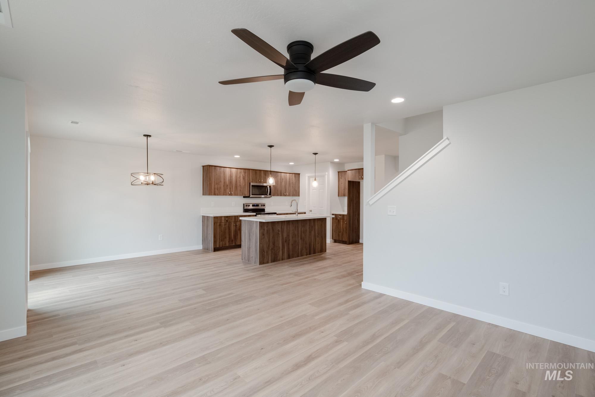 Kitchen featuring open floor plan, pendant lighting, light countertops, a kitchen island with sink, and recessed lighting