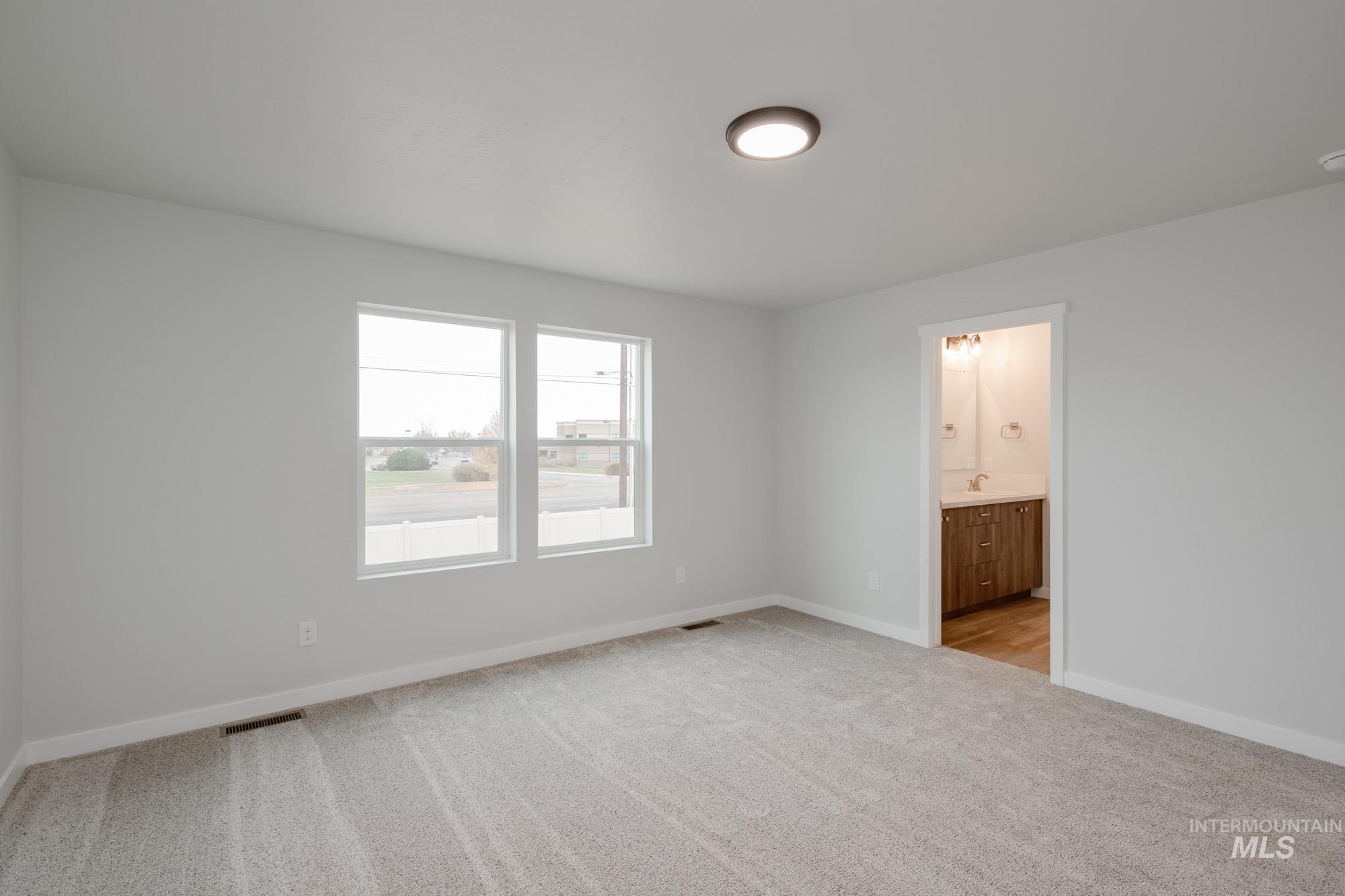 Unfurnished bedroom featuring light colored carpet and connected bathroom