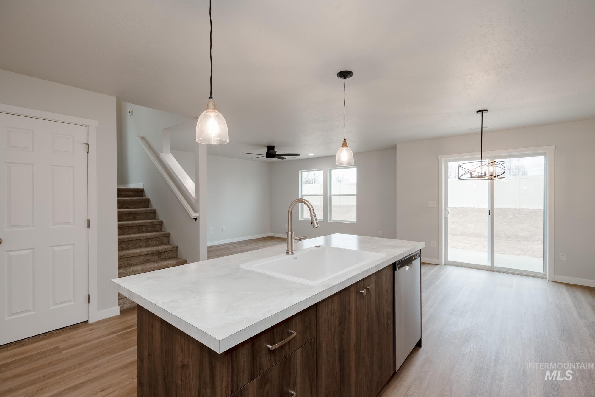 Kitchen featuring dark brown cabinetry, light countertops, light wood finished floors, and hanging light fixtures