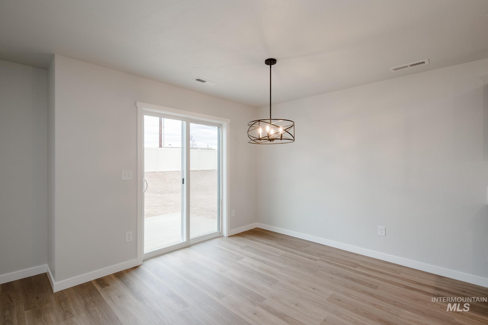 Spare room with a chandelier and light wood-style floors