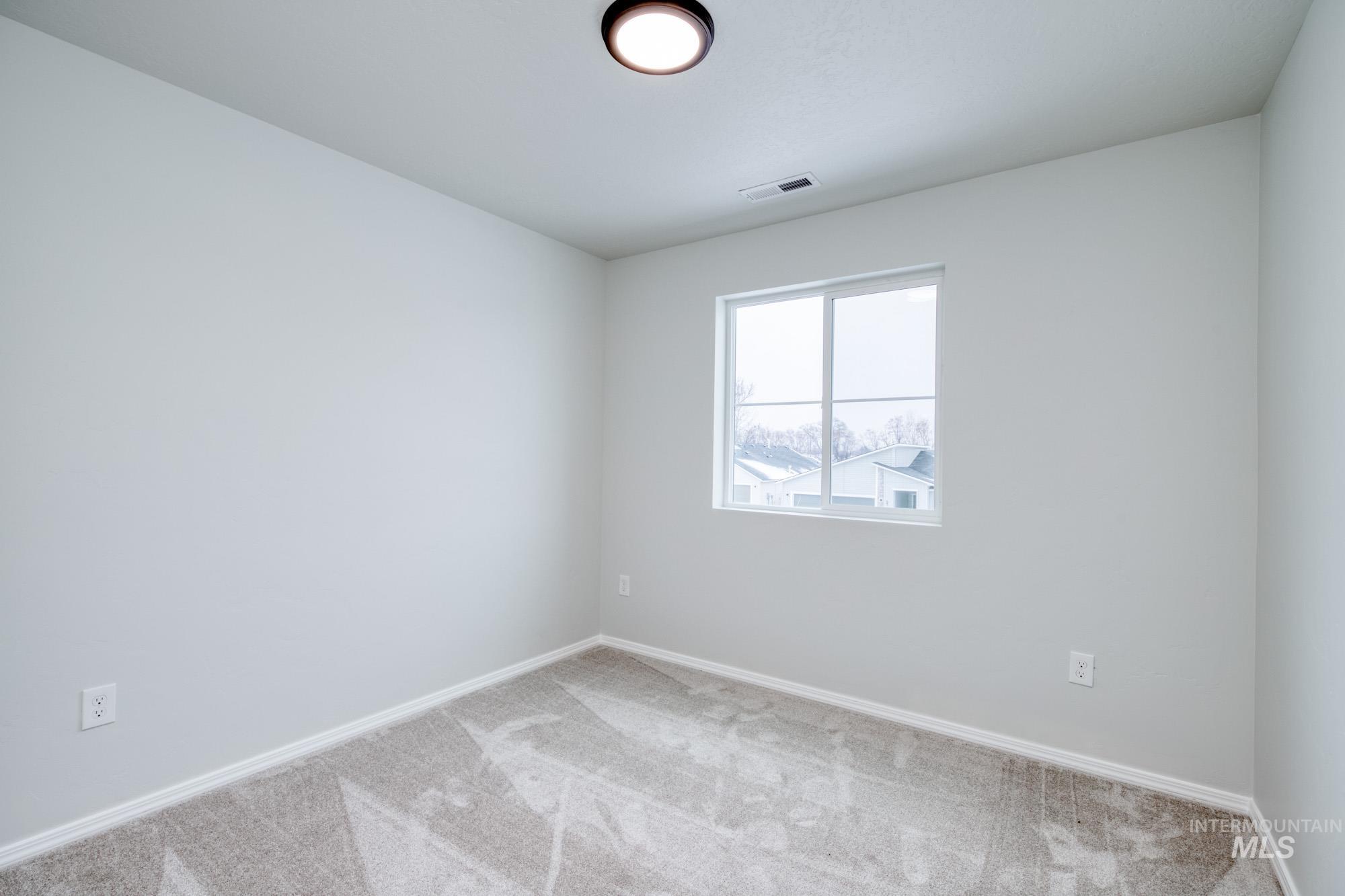 Spare room featuring carpet flooring and baseboards