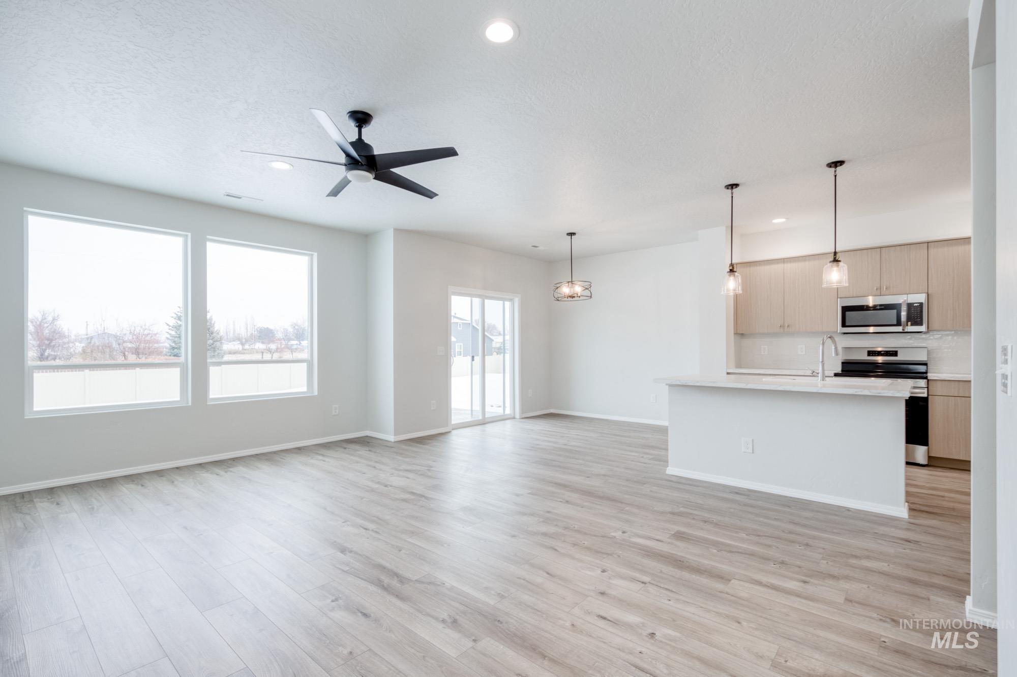 Unfurnished living room featuring light wood-type flooring, ceiling fan, and recessed lighting