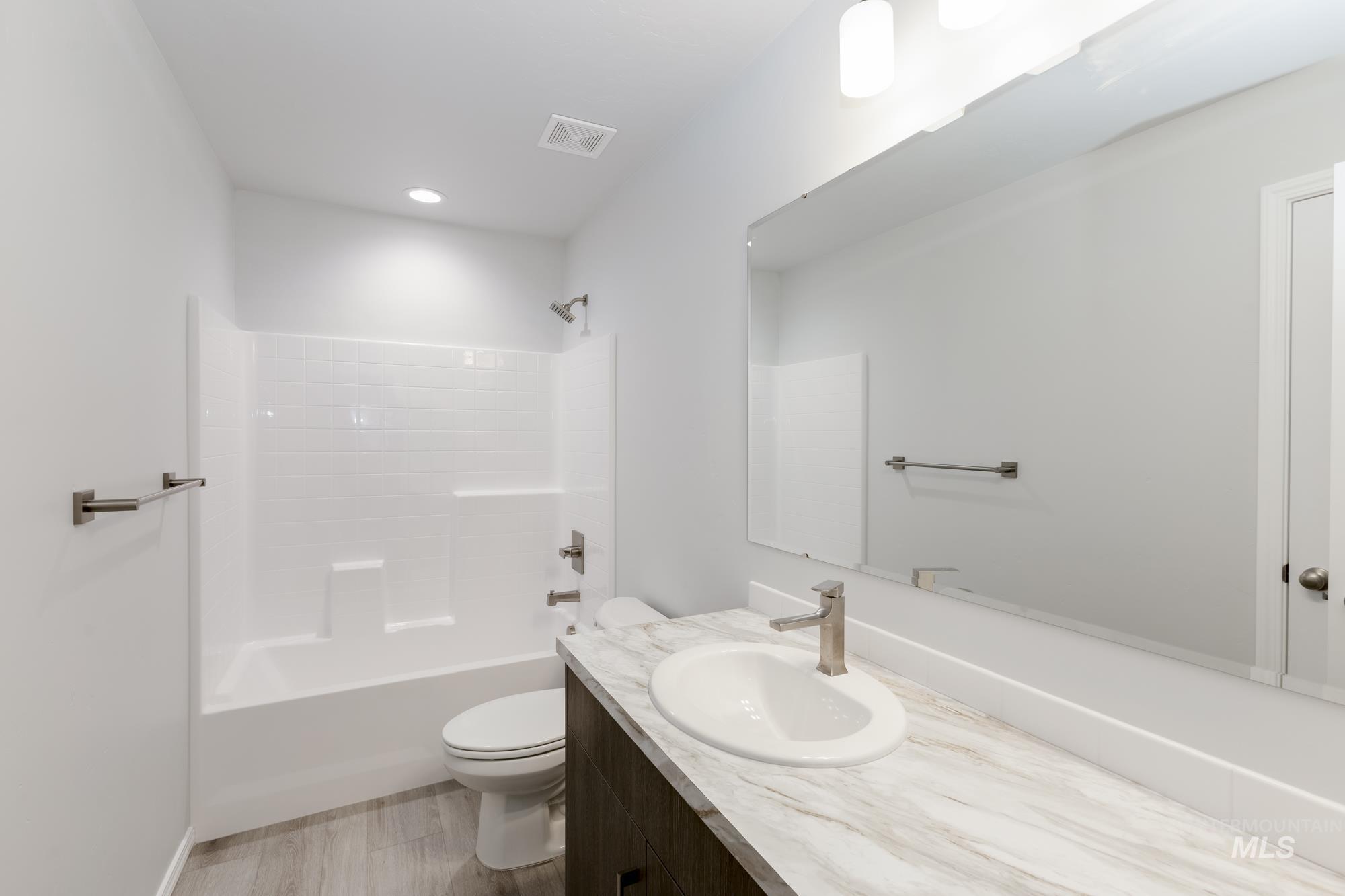 Bathroom featuring  shower combination, light wood-type flooring, and vanity
